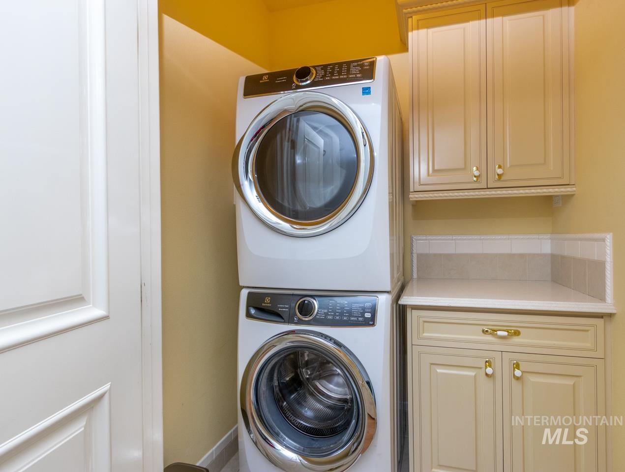 Laundry room featuring stacked washer and clothes dryer and cabinet space