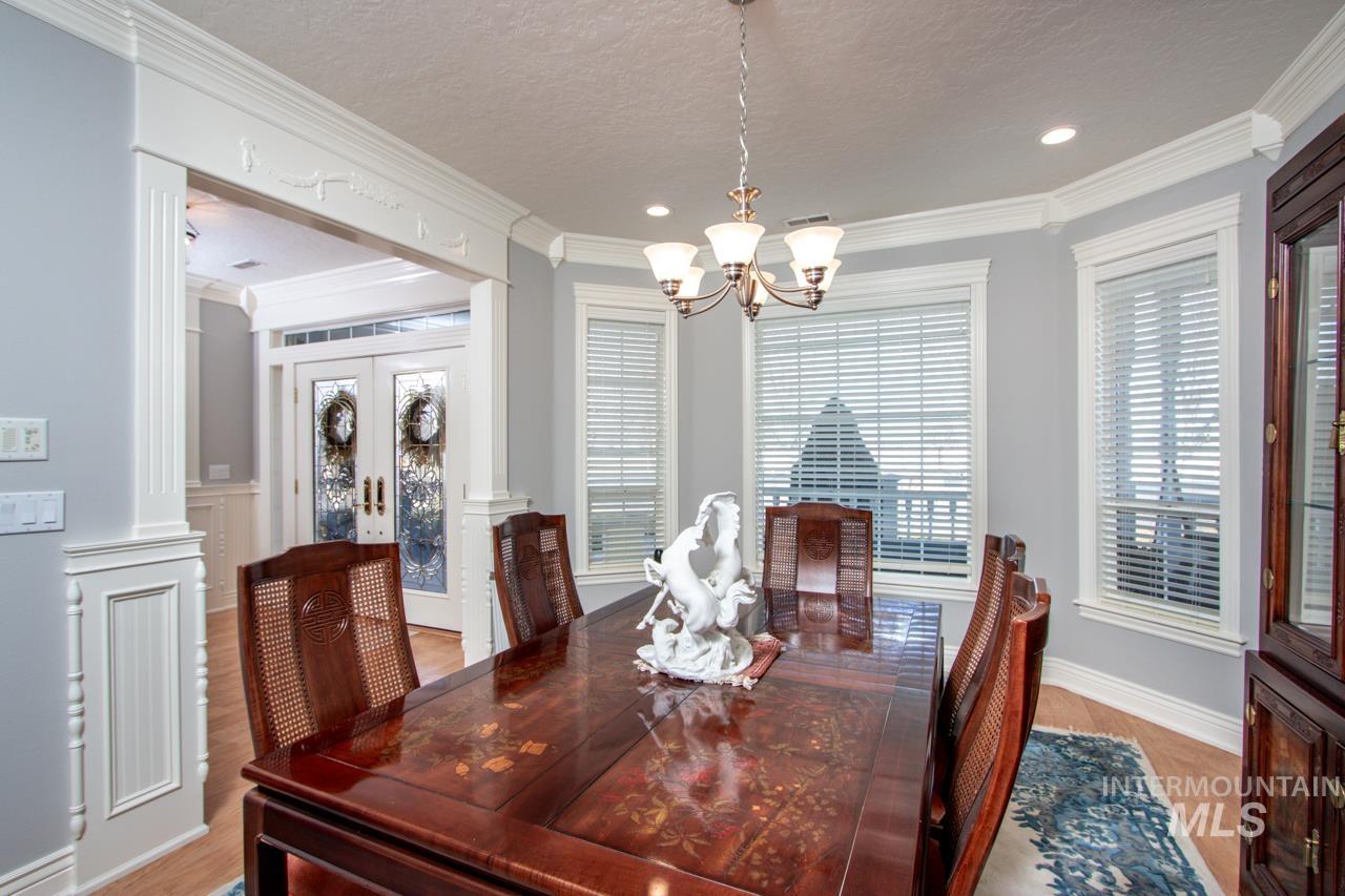 Dining area with a chandelier, crown molding, a textured ceiling, and light wood-type flooring