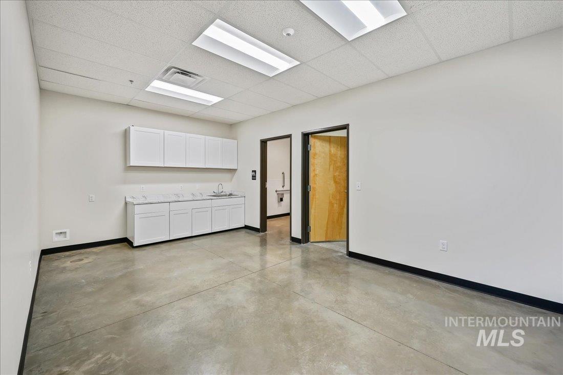 Empty room with a paneled ceiling and finished concrete floors