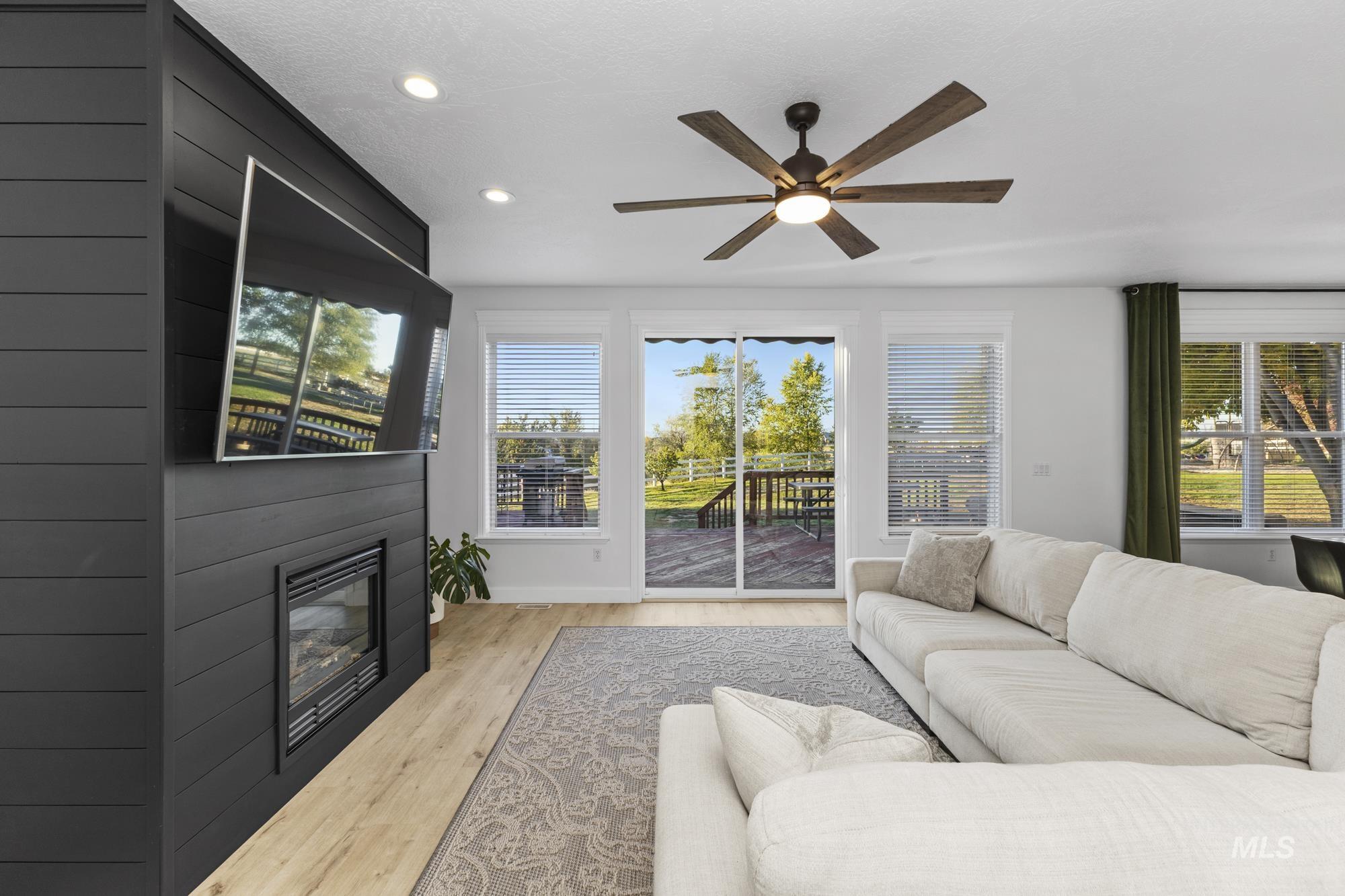 Living room featuring light wood-style flooring, ceiling fan, and recessed lighting