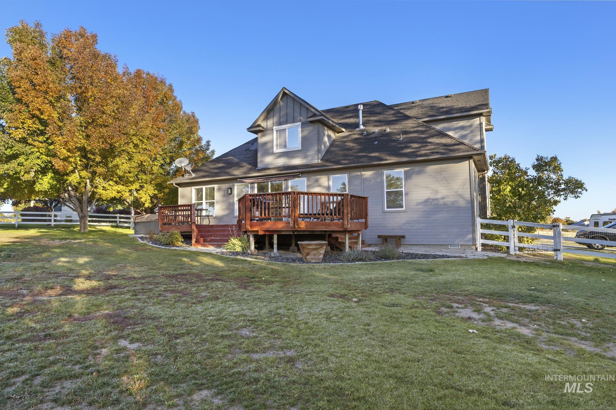 Back of property with a fenced backyard, a wooden deck, and board and batten siding