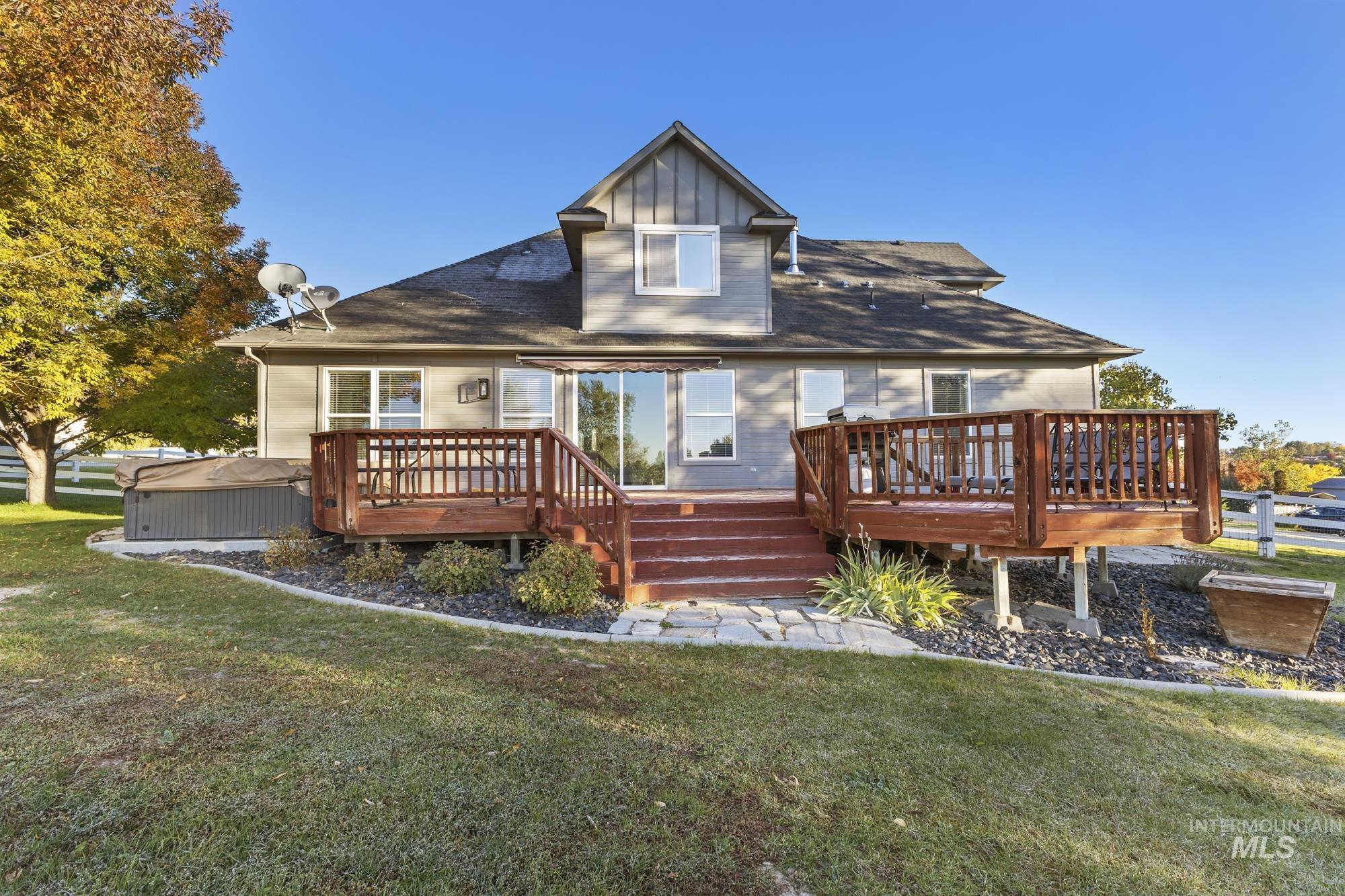 Back of property with a lawn, a wooden deck, and a shingled roof