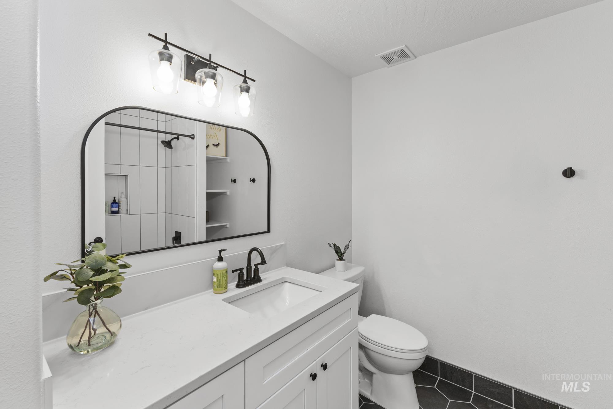 Bathroom with vanity, dark tile patterned floors, and a shower