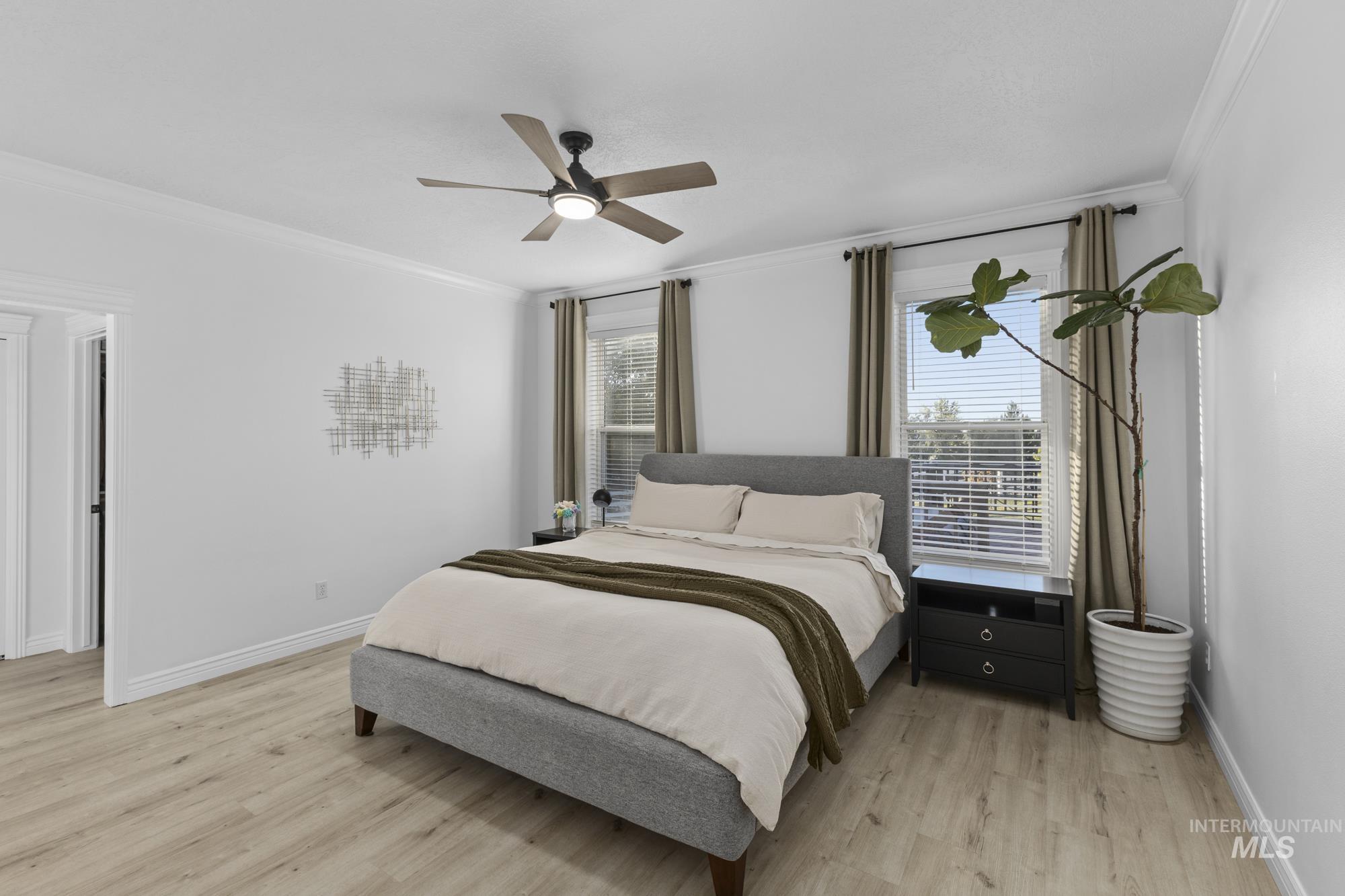 Bedroom featuring crown molding, light wood finished floors, multiple windows, and ceiling fan