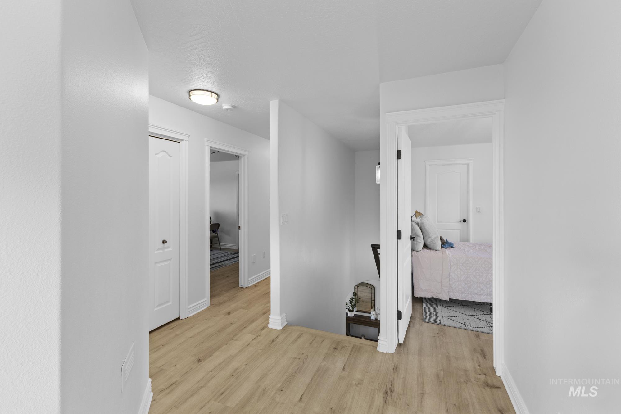 Hallway with light wood-type flooring and an upstairs landing
