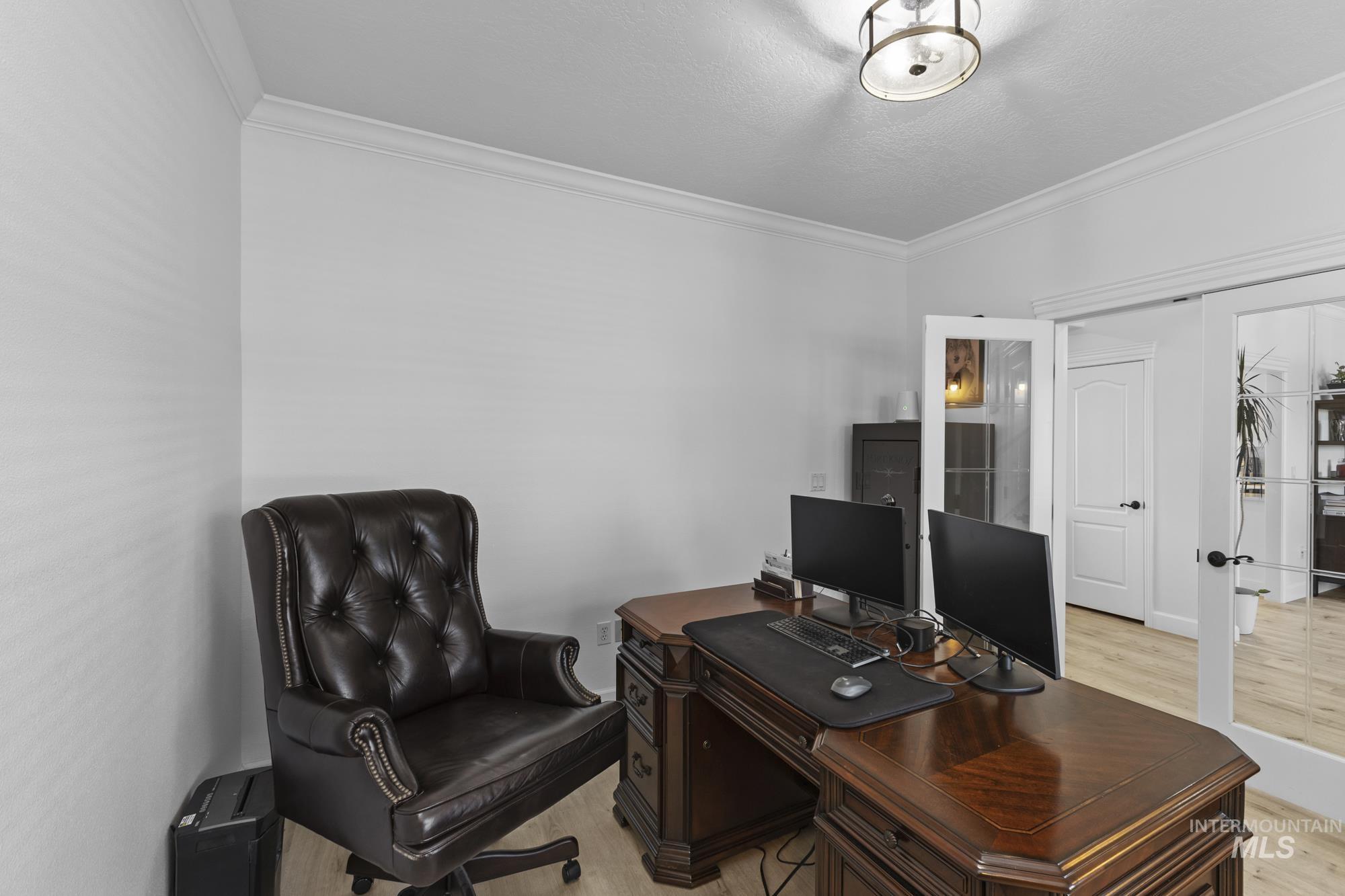 Office space with ornamental molding and light wood-style flooring