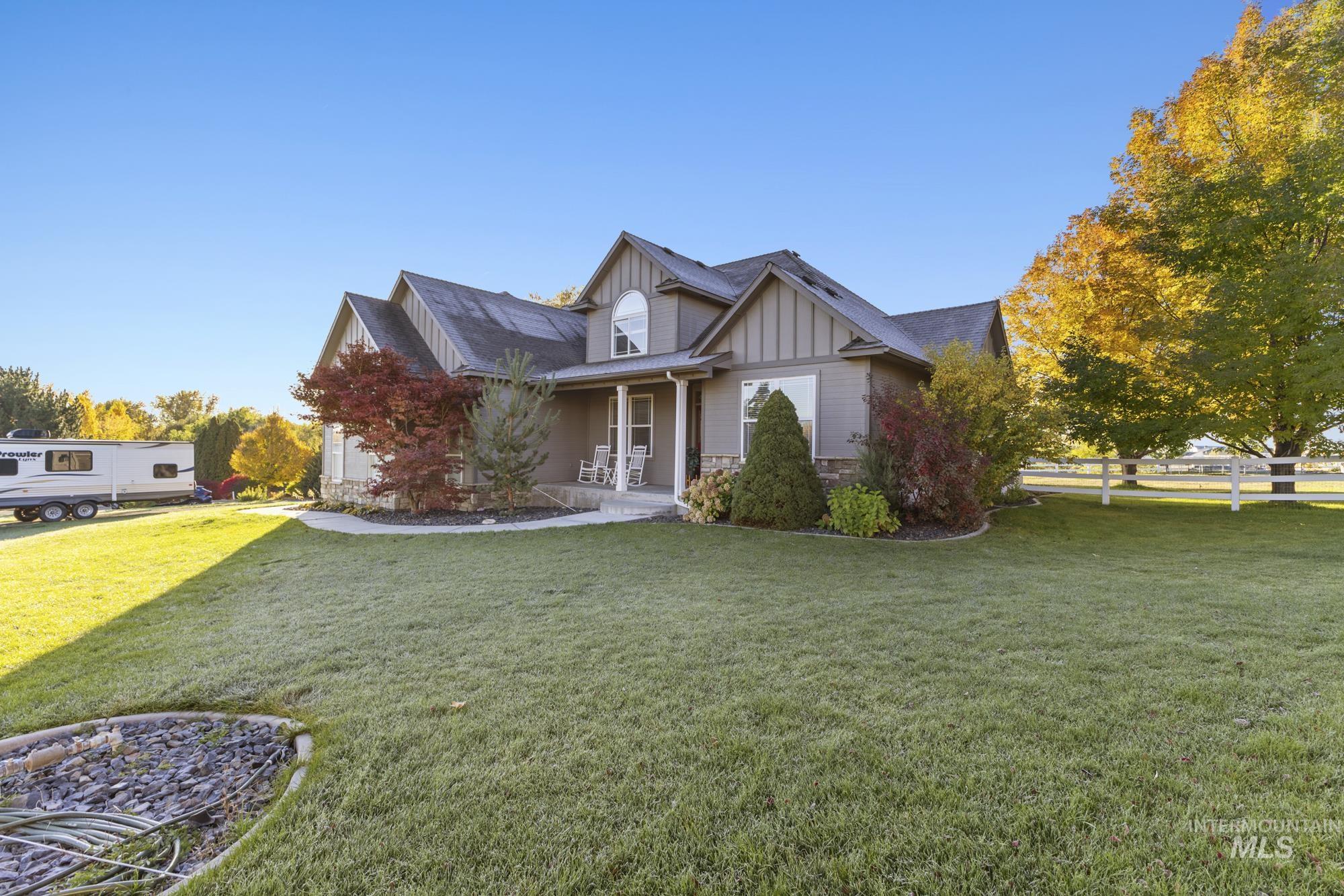 View of front of property with board and batten siding, covered porch, stone siding, and a front lawn