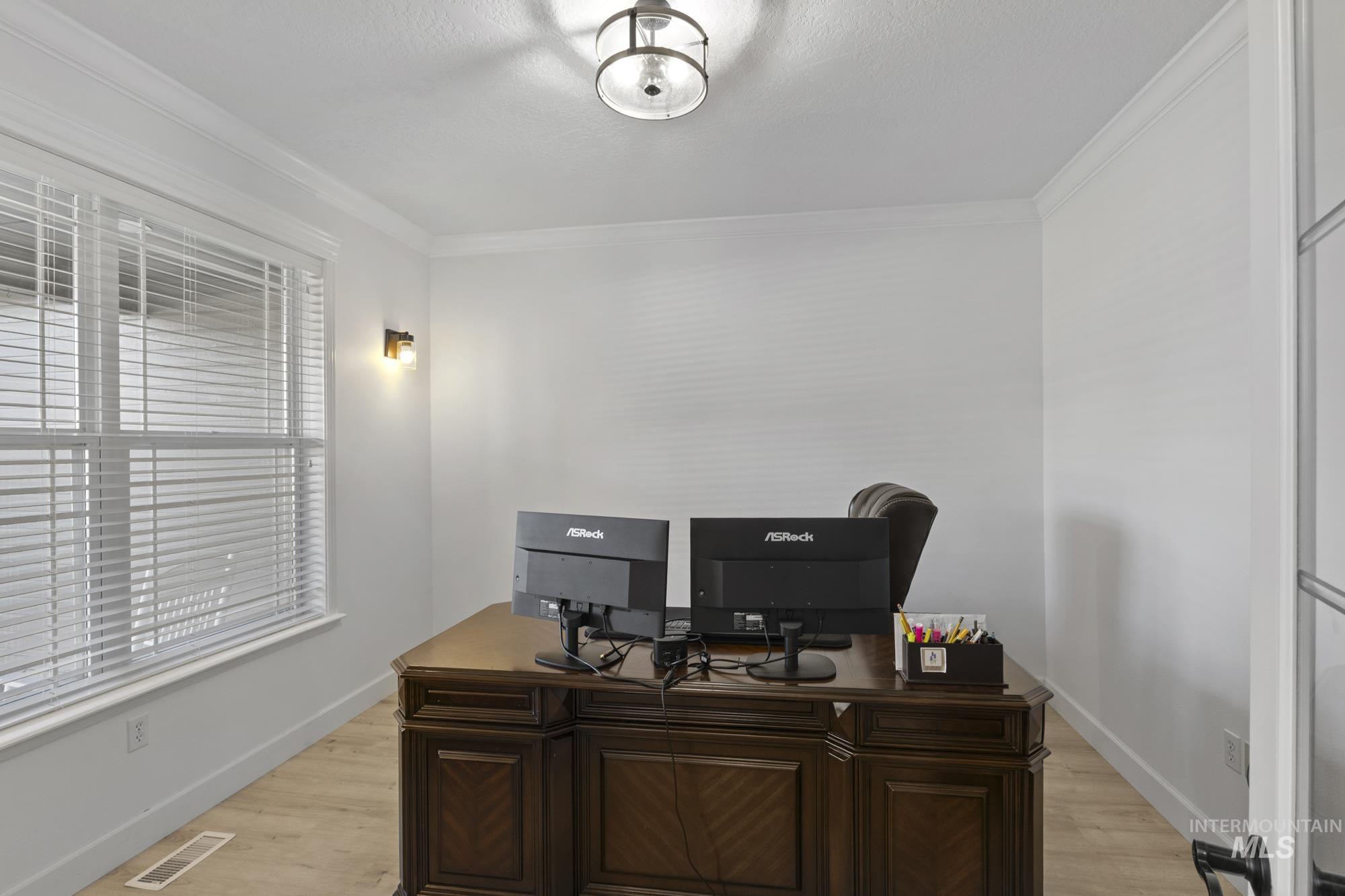Office area with light wood-style flooring and crown molding