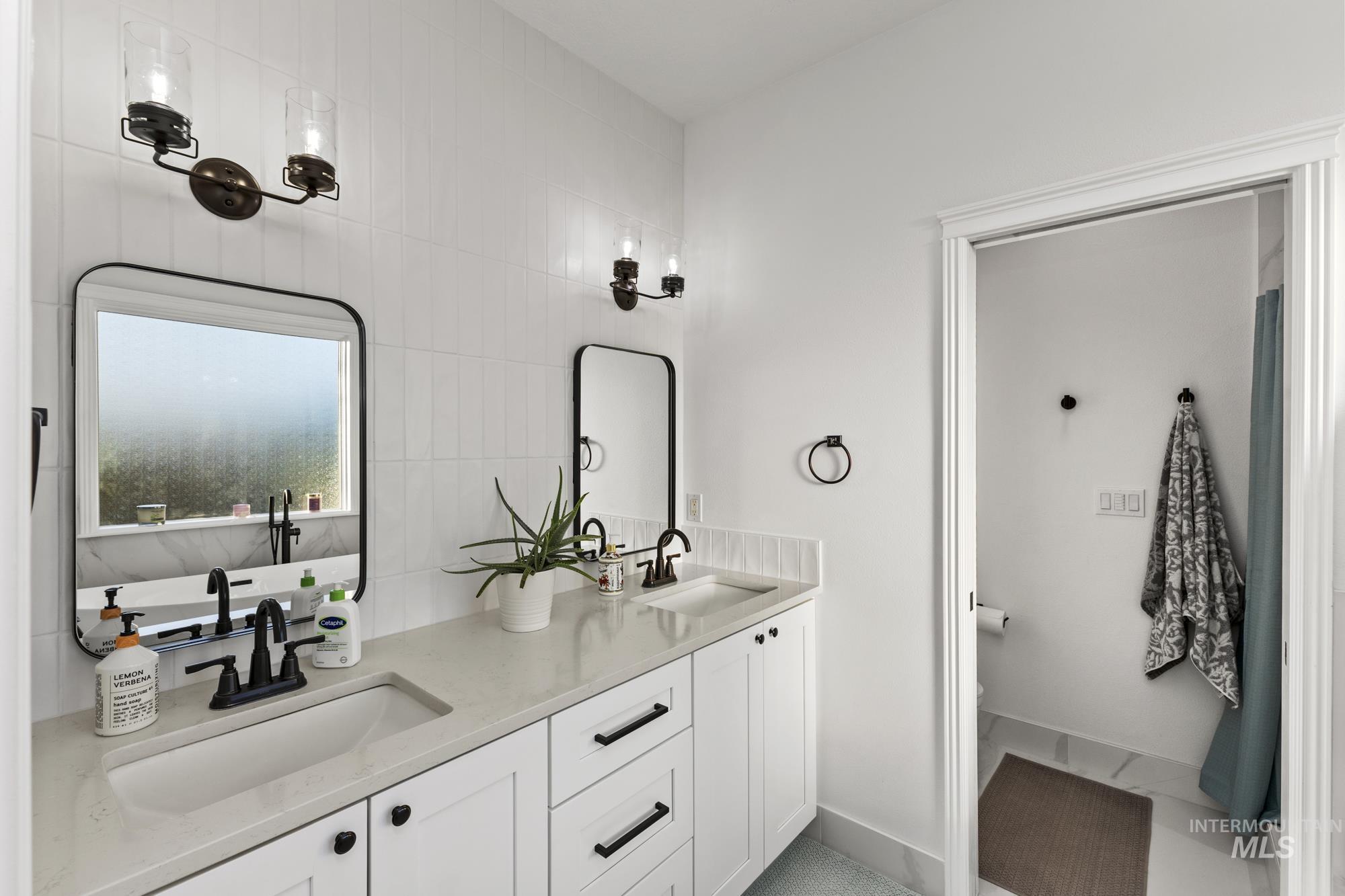 Bathroom with double vanity, light tile patterned floors, and tile walls