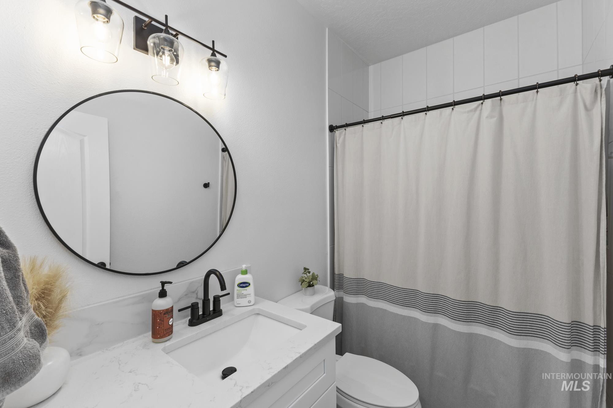 Full bathroom with curtained shower and vanity