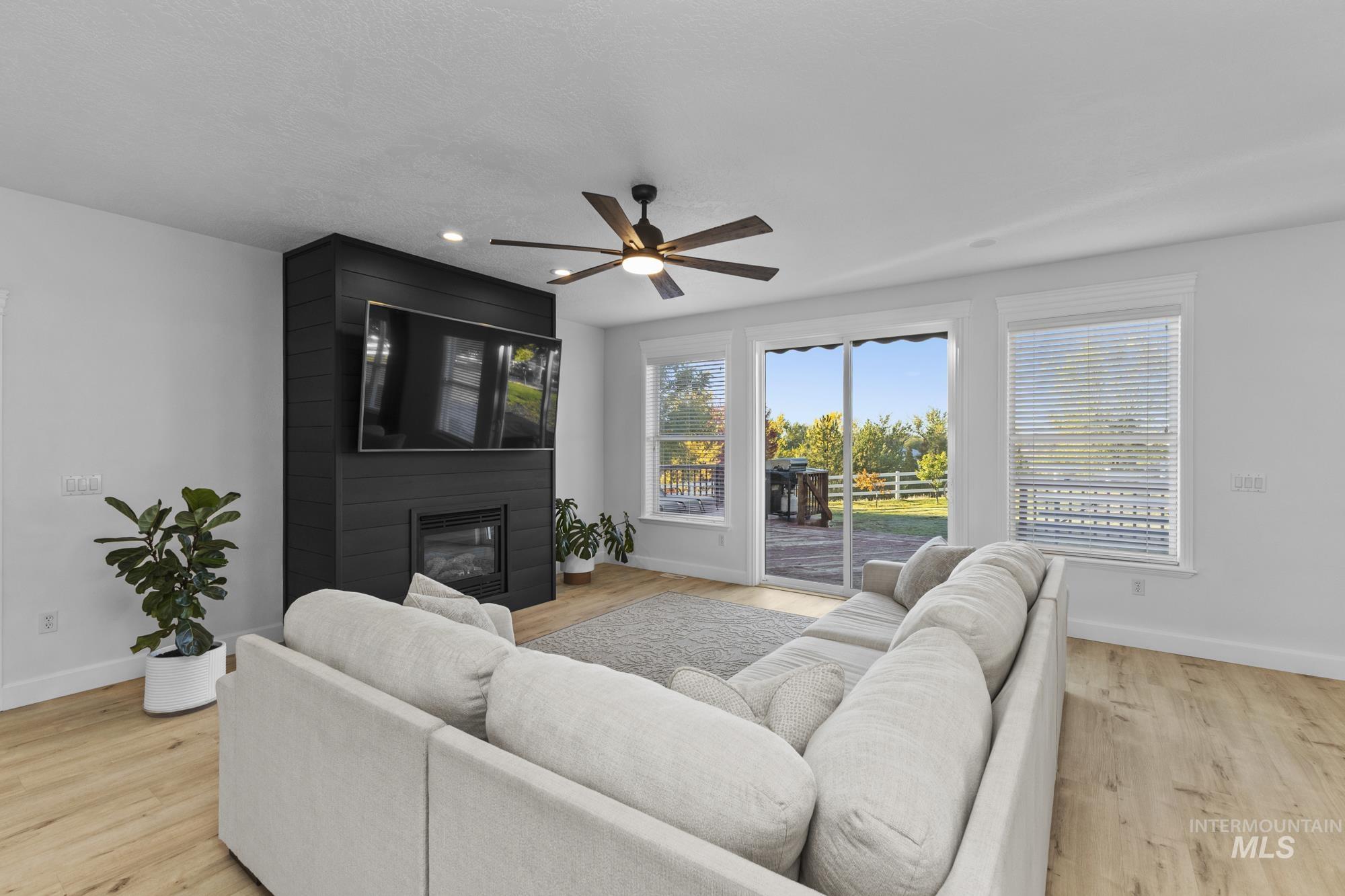Living room featuring light wood-style floors, ceiling fan, a fireplace, and recessed lighting