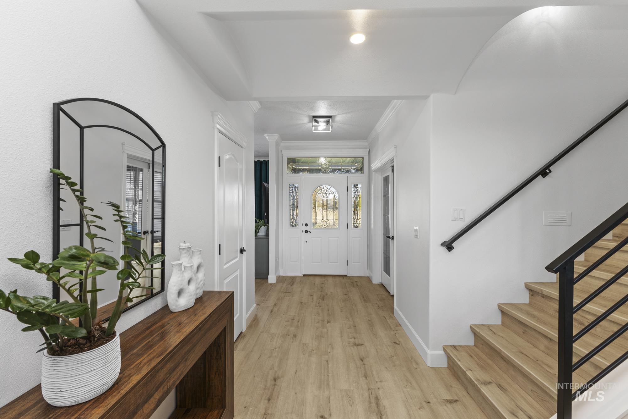 Entrance foyer with light wood-style floors, stairway, and crown molding