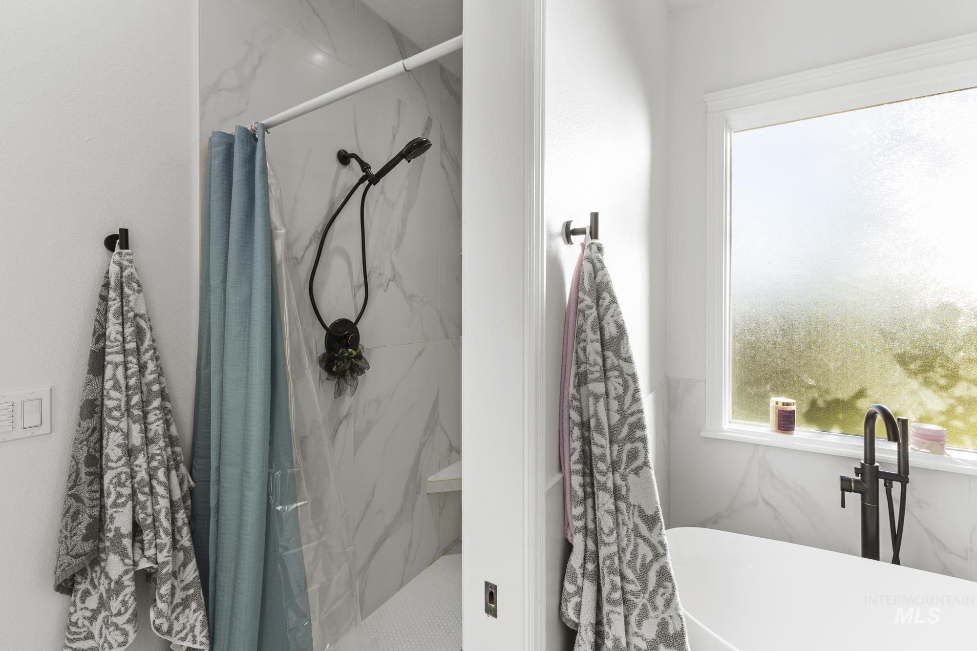 Full bath with plenty of natural light, a freestanding tub, and a marble finish shower