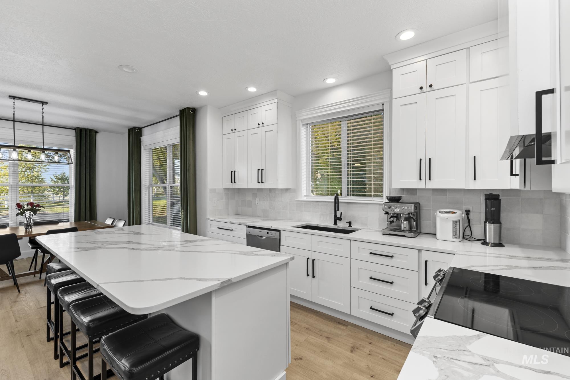 Kitchen with a breakfast bar area, decorative backsplash, light stone counters, a center island, and pendant lighting