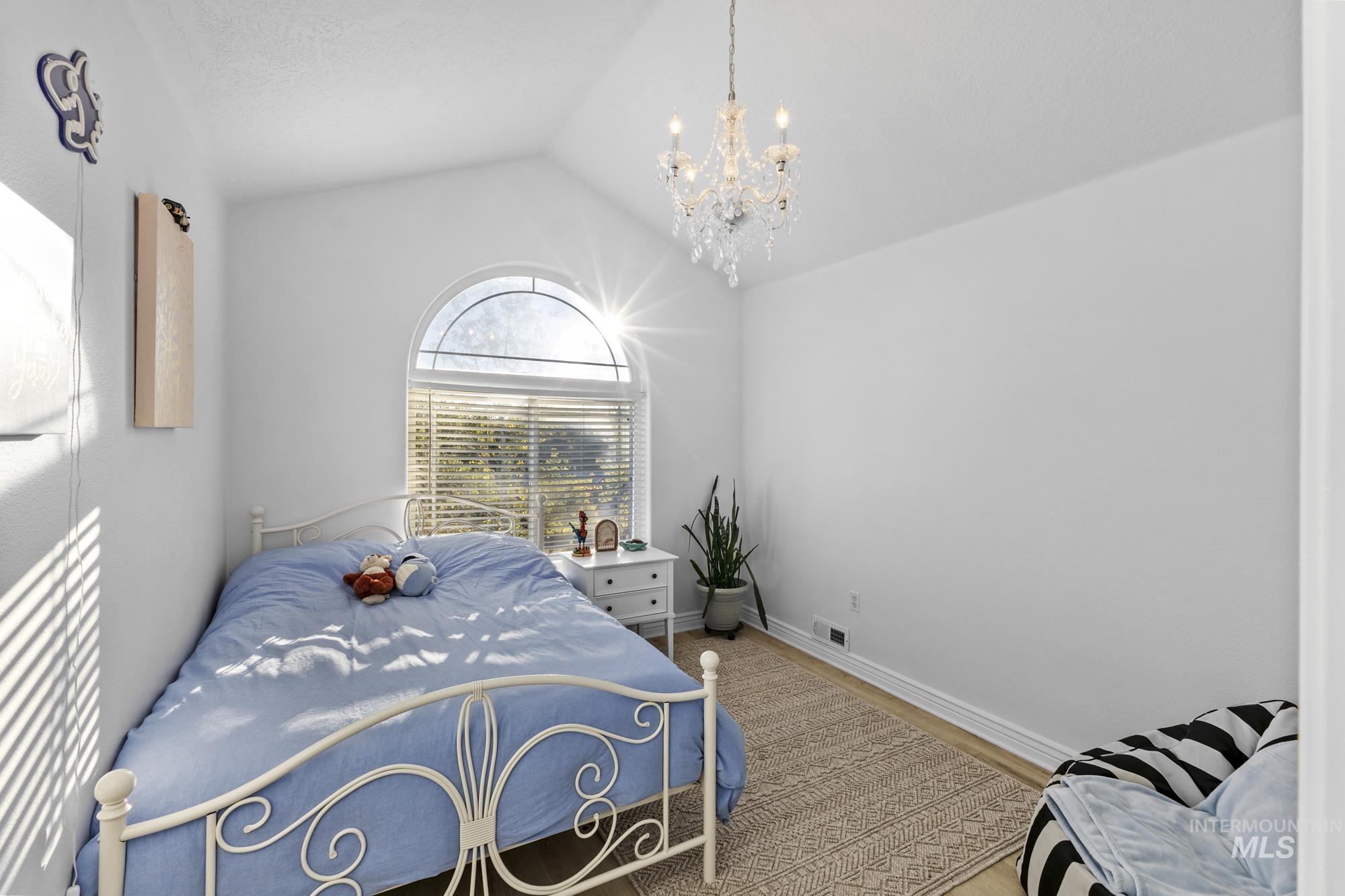 Bedroom with lofted ceiling, a chandelier, and wood finished floors
