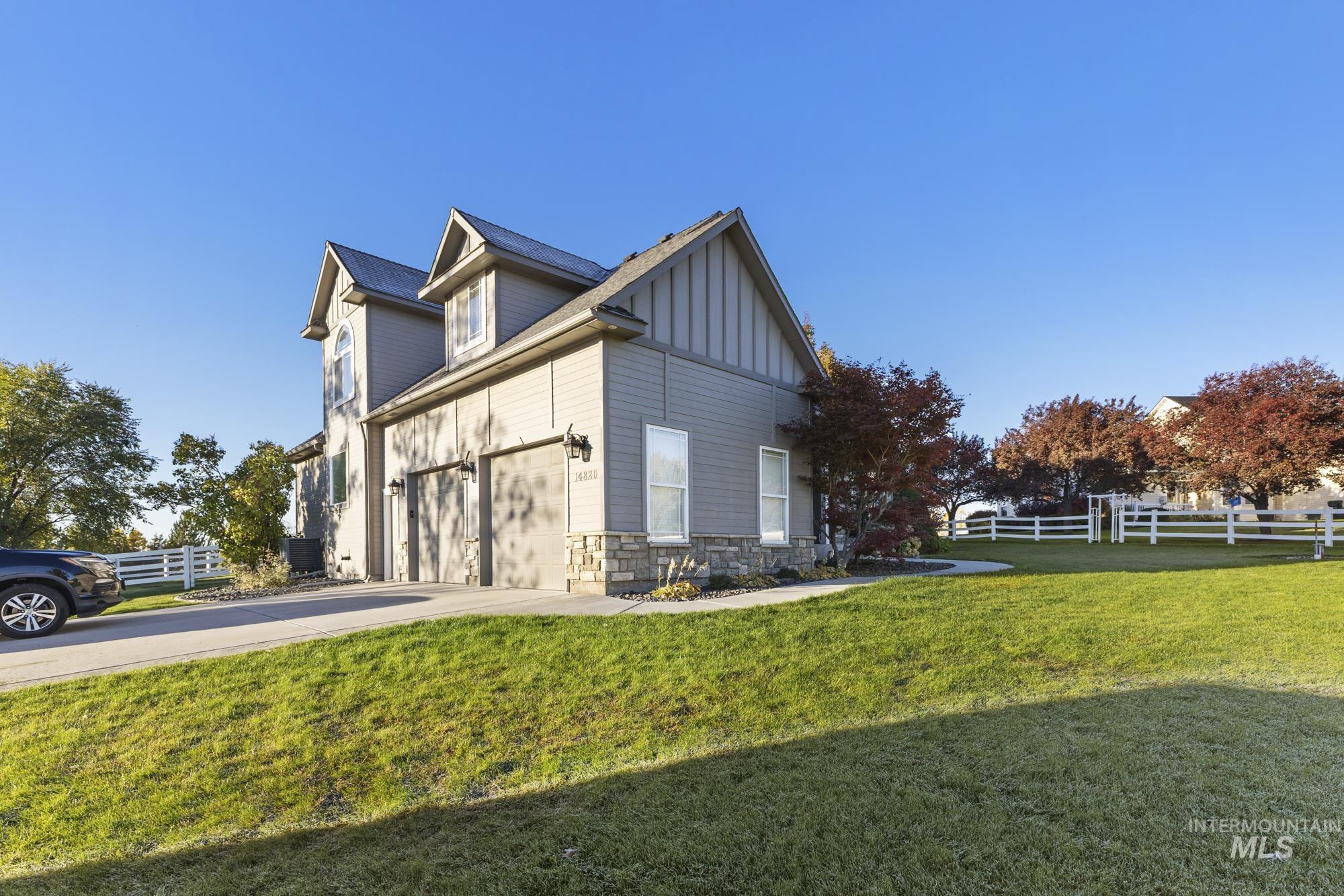 View of side of property with board and batten siding, concrete driveway, and stone siding