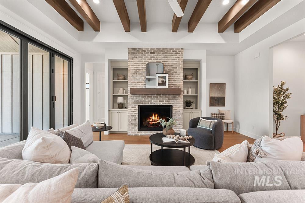 Living area featuring a fireplace, wood finished floors, beamed ceiling, recessed lighting, and built in shelves