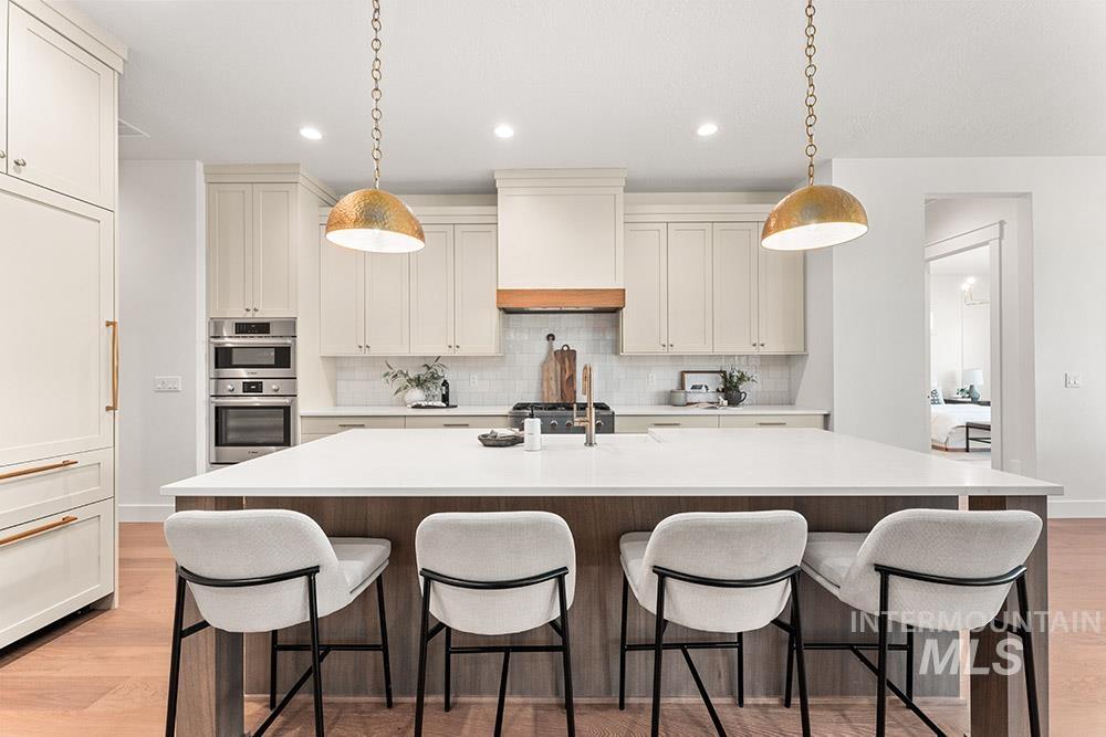 Kitchen with light wood-type flooring, tasteful backsplash, a center island with sink, recessed lighting, and a kitchen breakfast bar