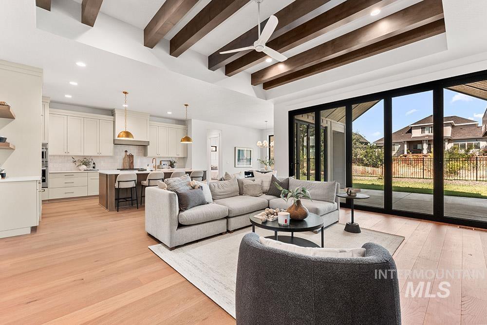 Living area featuring beamed ceiling, light wood-style floors, ceiling fan, a chandelier, and recessed lighting