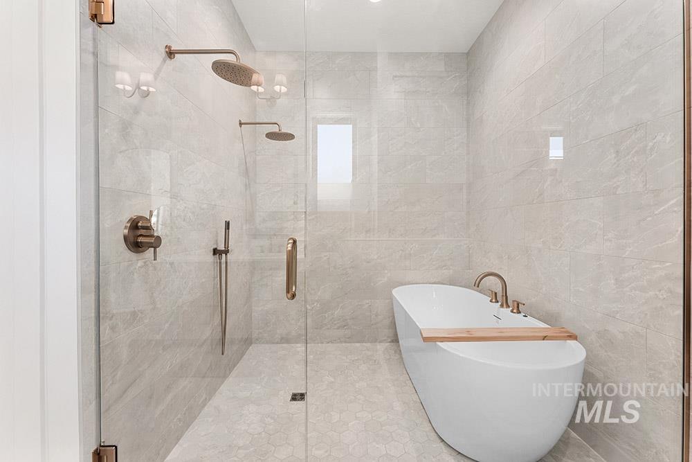 Full bath featuring a freestanding bath, a shower stall, and tile walls