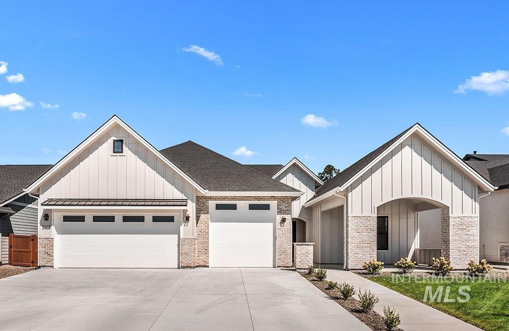 Modern farmhouse style home featuring board and batten siding, an attached garage, driveway, and a standing seam roof
