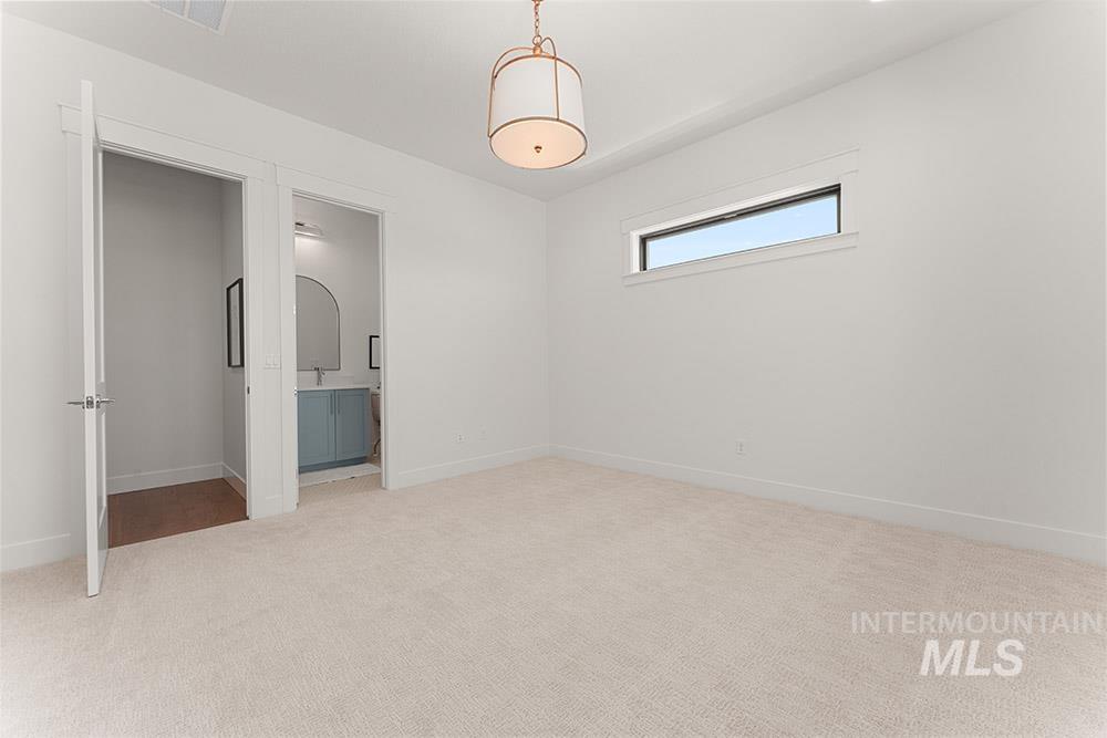 Unfurnished bedroom with light carpet and ensuite bathroom