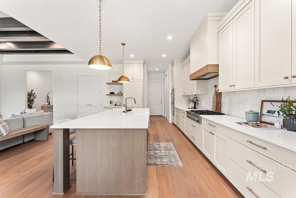 Kitchen with light wood-style flooring, backsplash, a kitchen bar, open floor plan, and recessed lighting