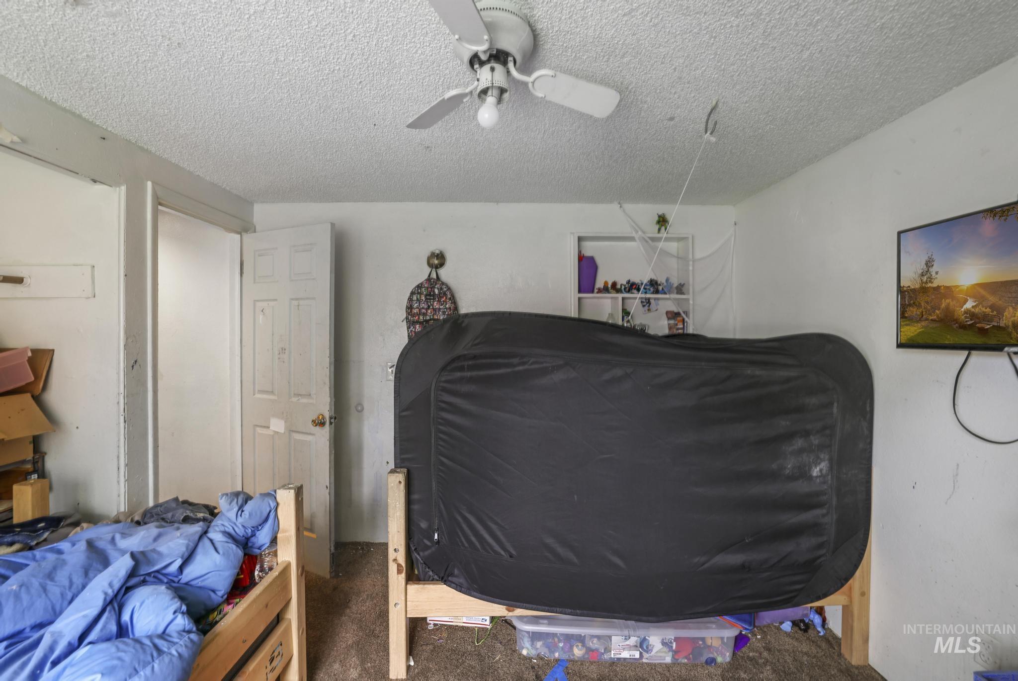 Carpeted bedroom featuring a textured ceiling and a ceiling fan