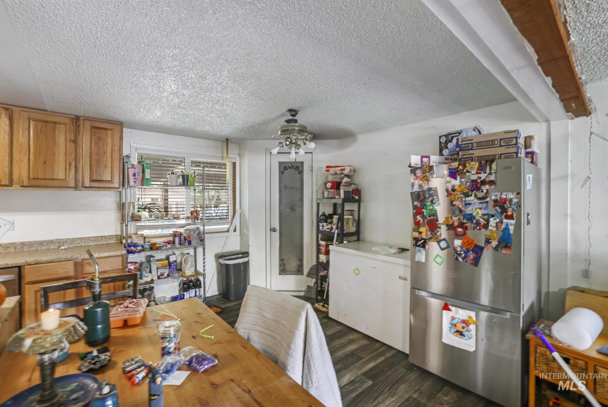 Kitchen with stainless steel appliances, light countertops, dark wood-type flooring, a textured ceiling, and a ceiling fan