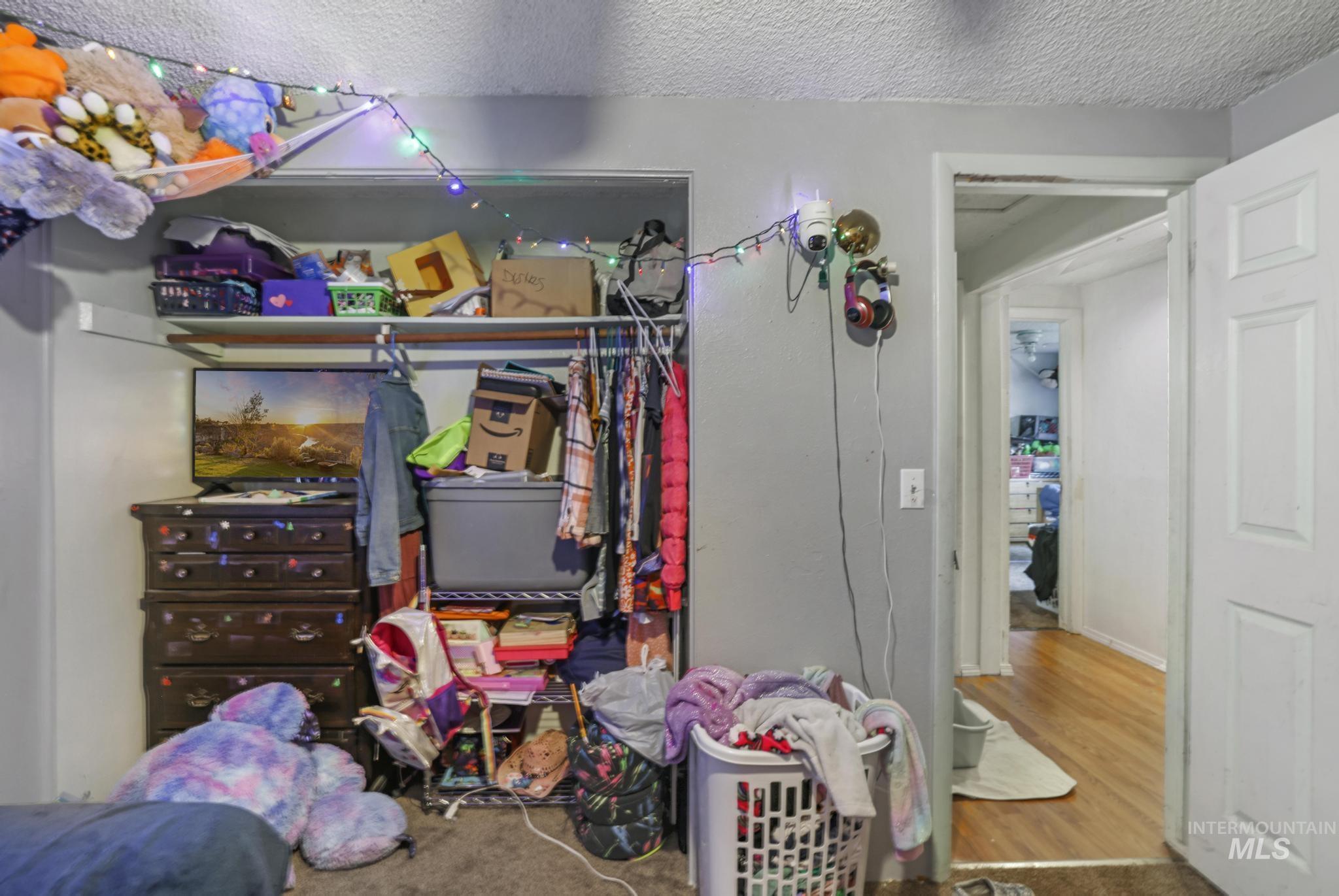 Bedroom with a textured ceiling, a closet, wood finished floors, and carpet flooring