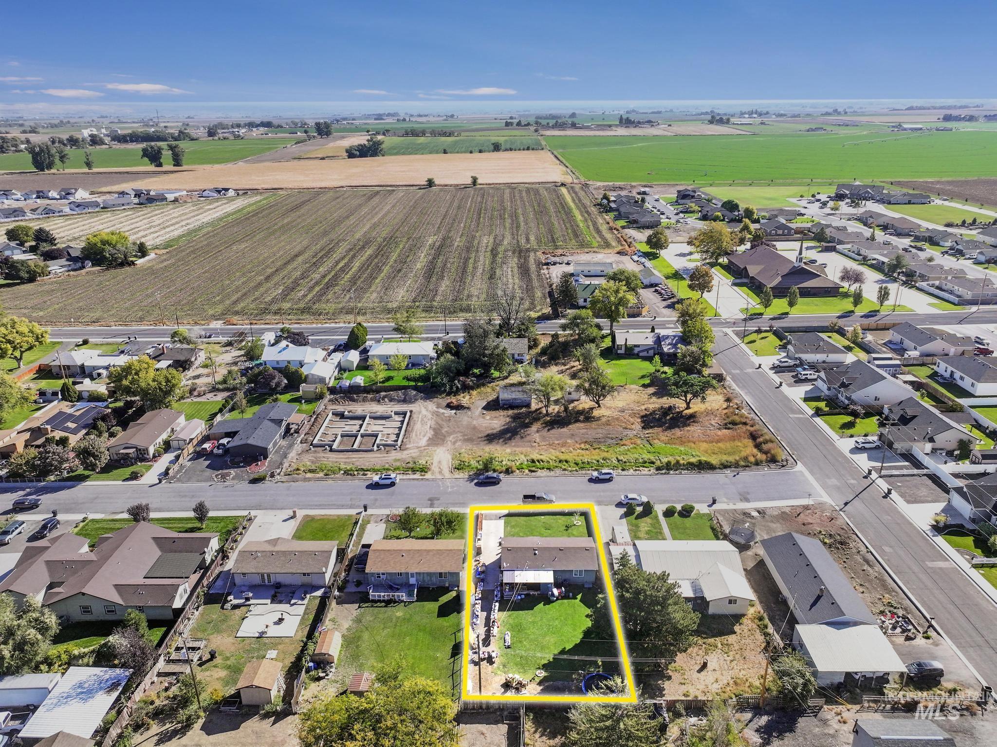 Aerial view of sparsely populated area with property parcel outlined and nearby suburban area