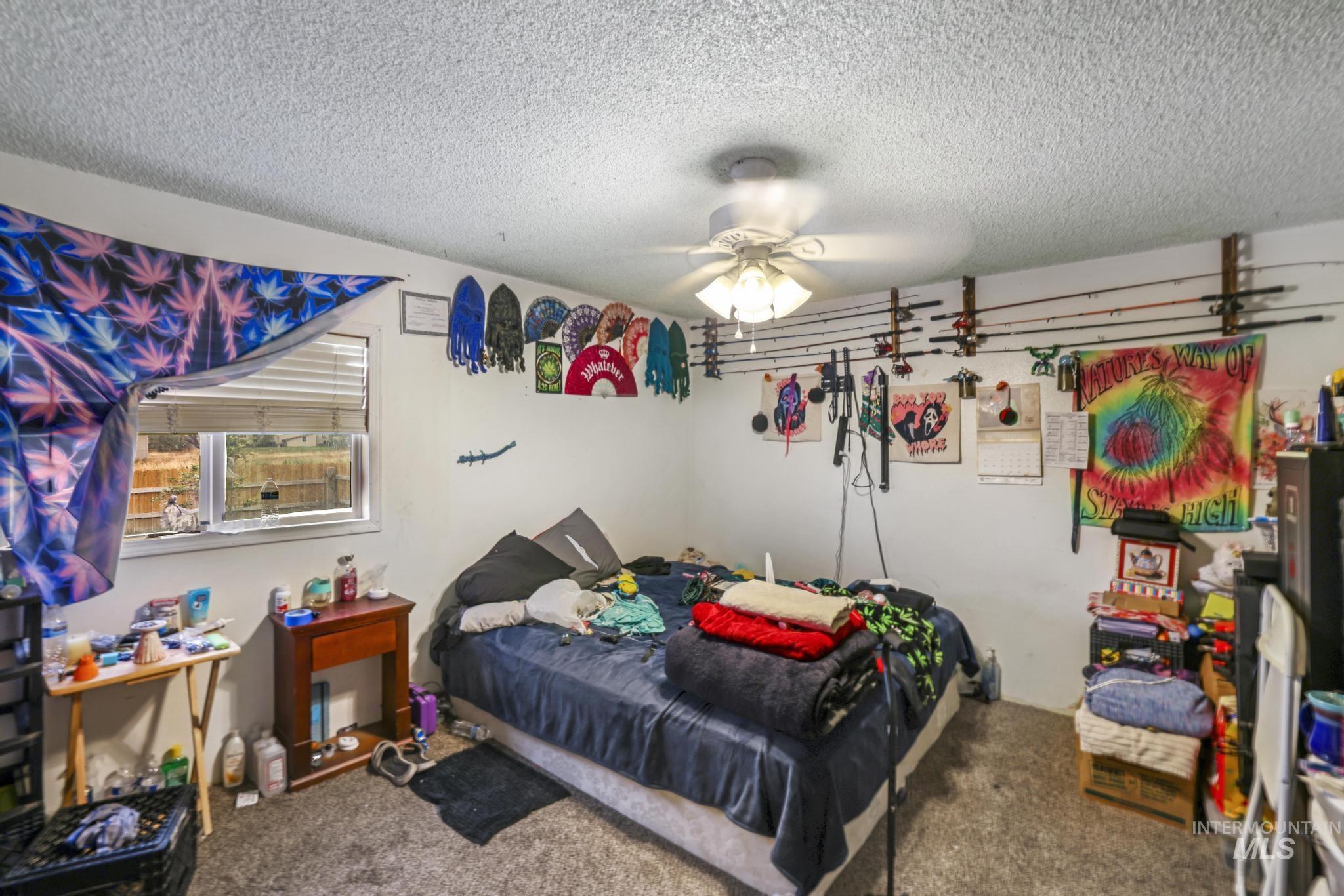 Carpeted bedroom with a textured ceiling and ceiling fan