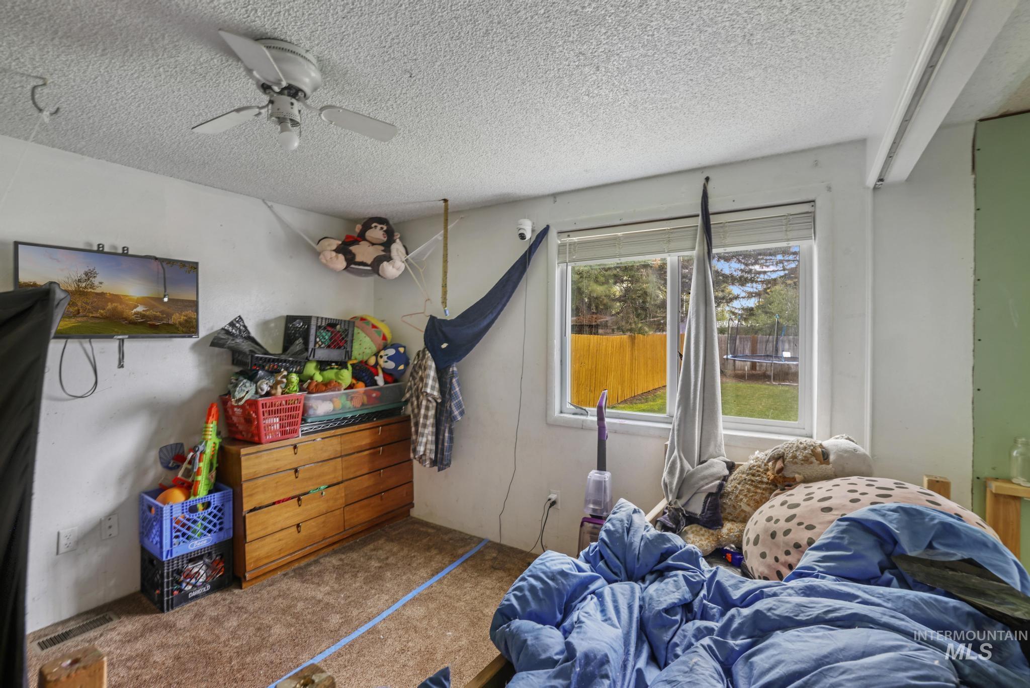 Carpeted bedroom with a textured ceiling and ceiling fan
