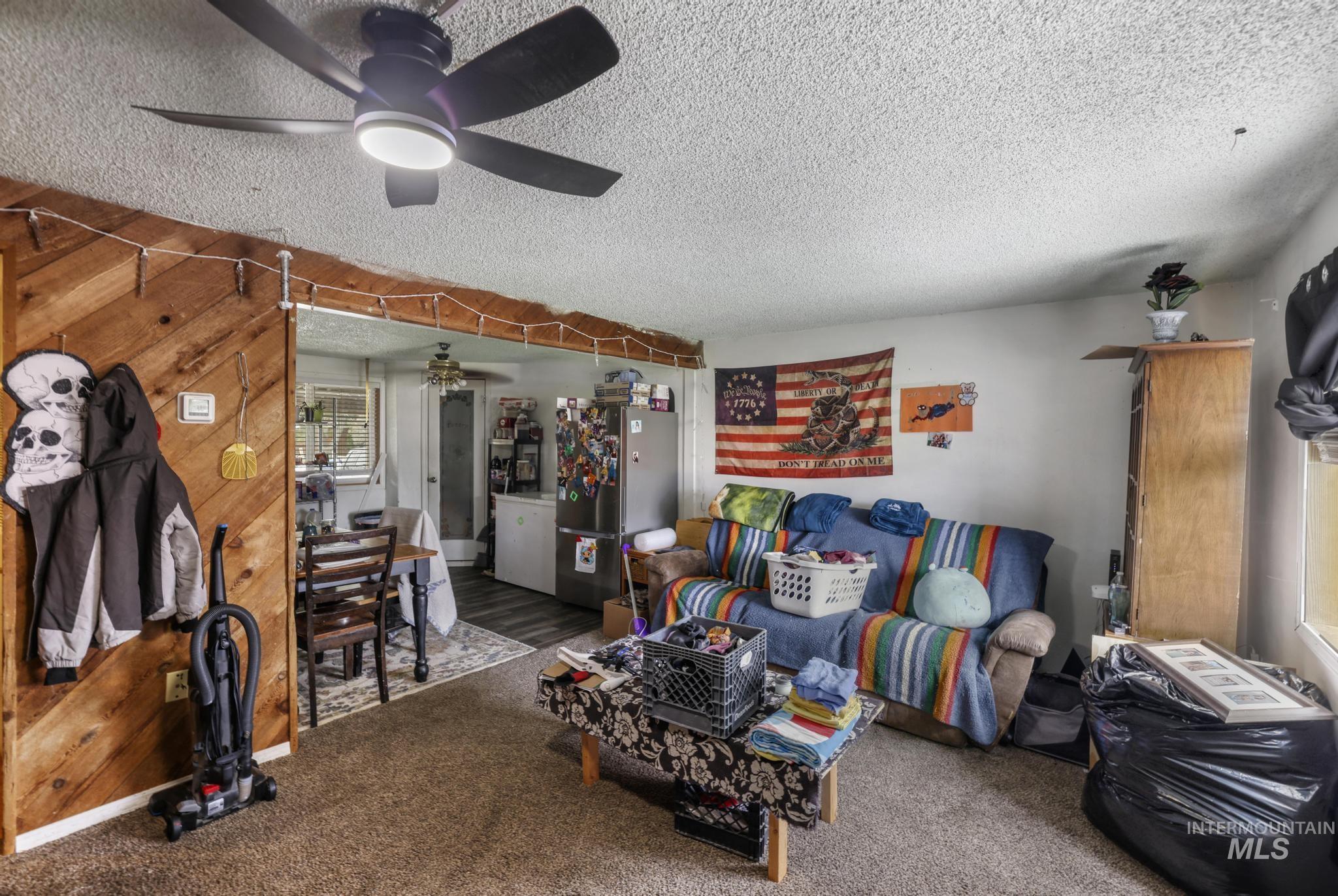 Carpeted living area featuring a textured ceiling and wooden walls