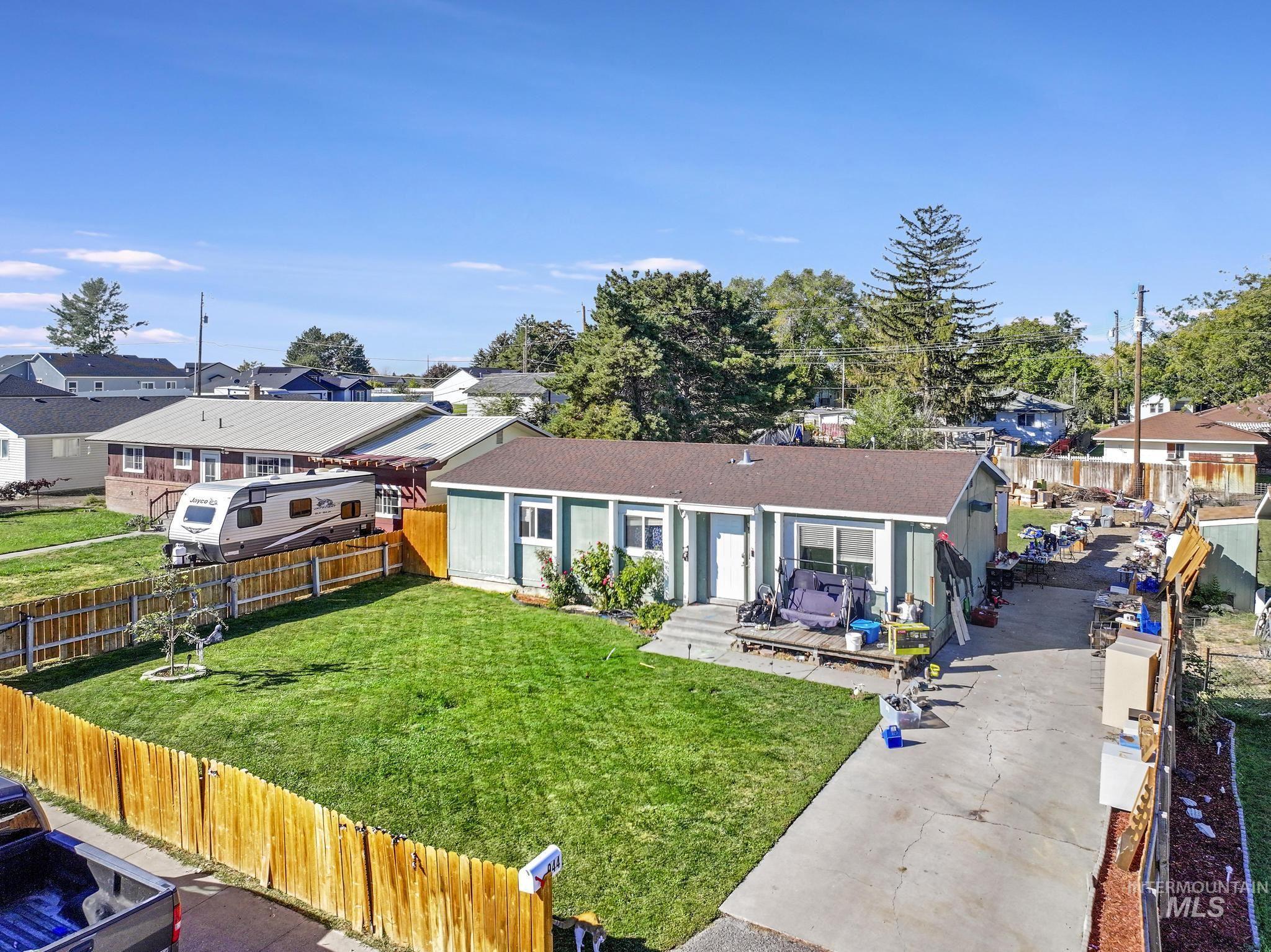 View of front of property featuring a fenced backyard, a residential view, a deck, and a shingled roof