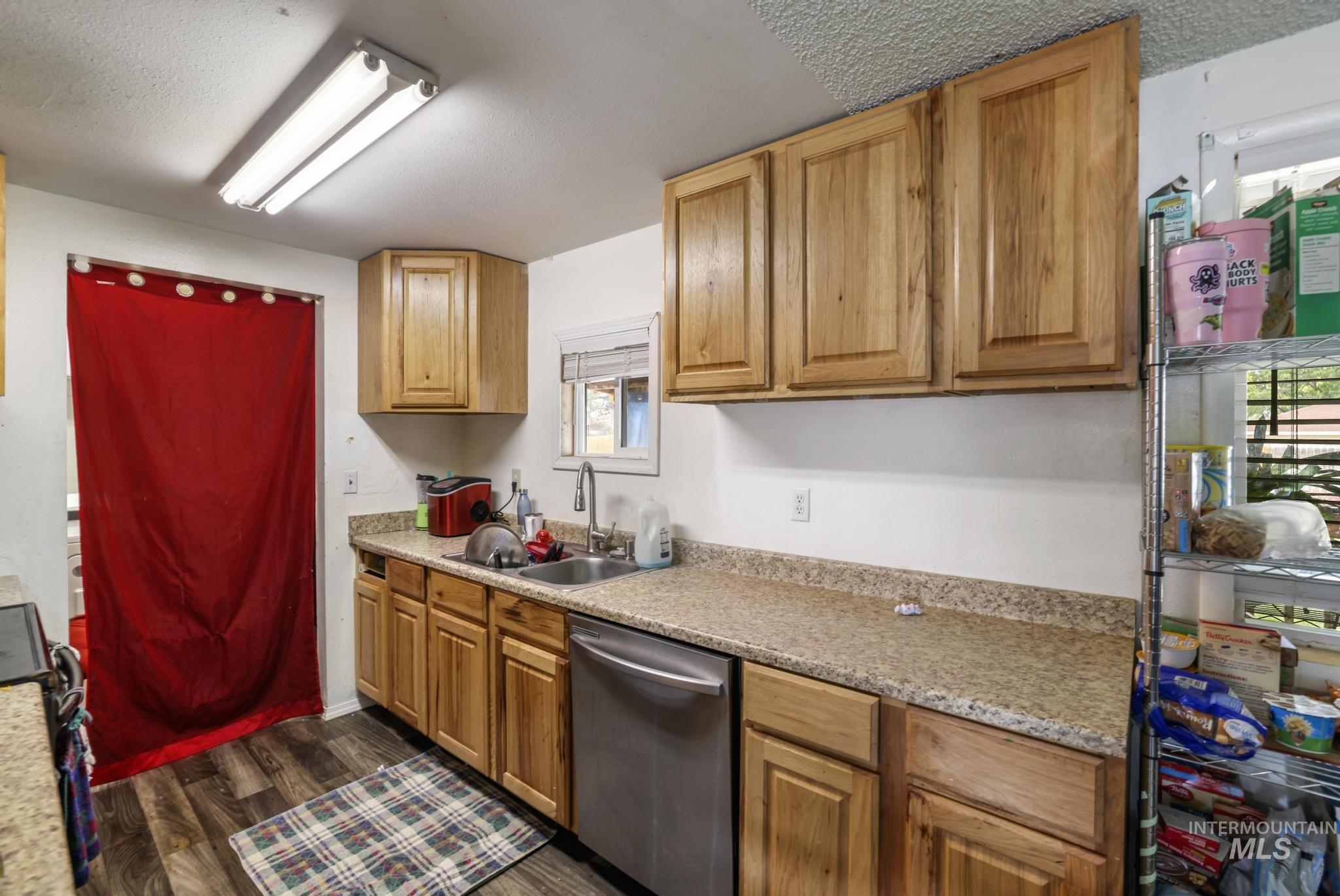 Kitchen featuring dishwasher, dark wood-style flooring, a textured ceiling, black stove, and brown cabinets