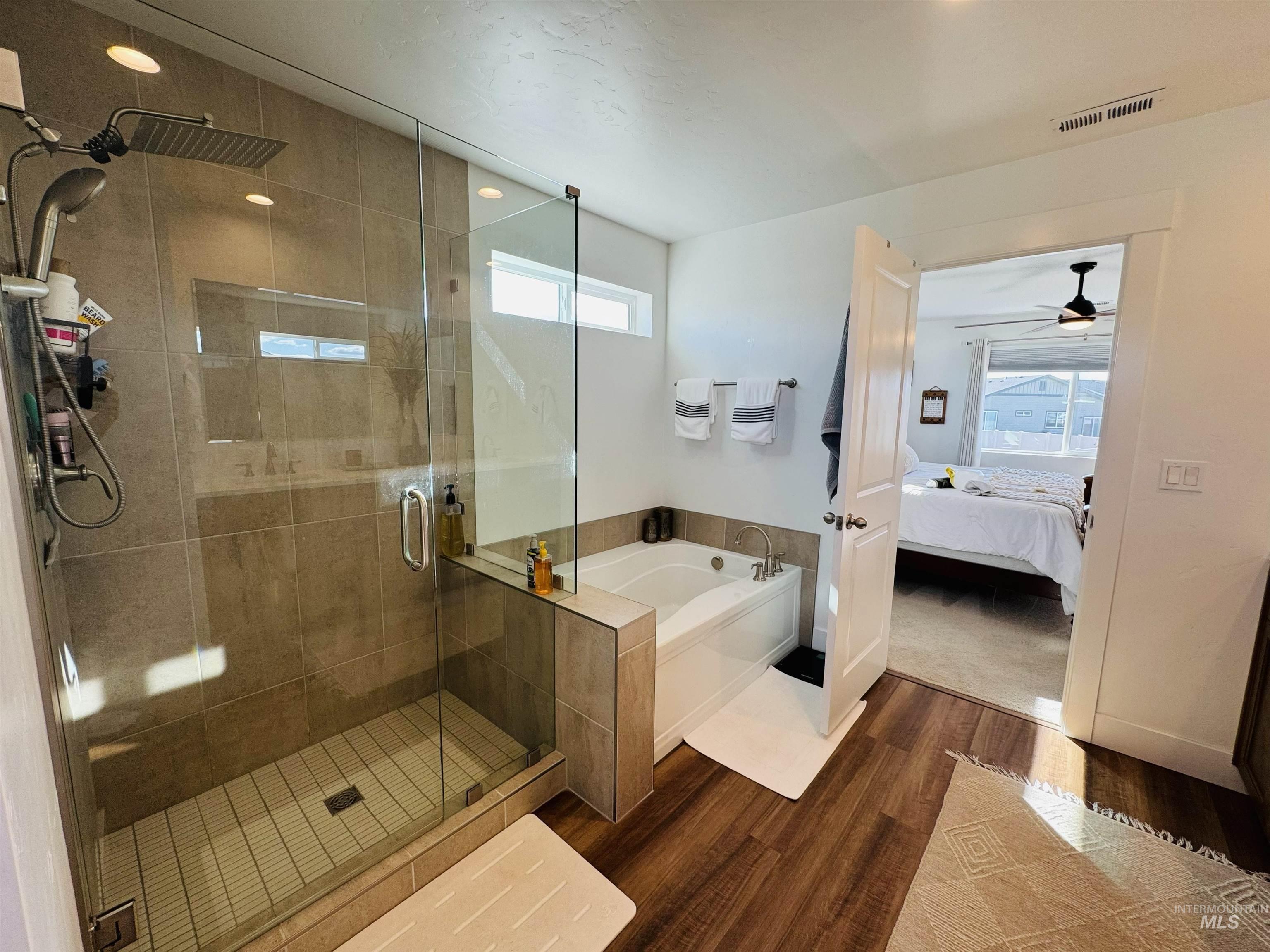 Bathroom featuring ensuite bath, plenty of natural light, a shower stall, and a bath