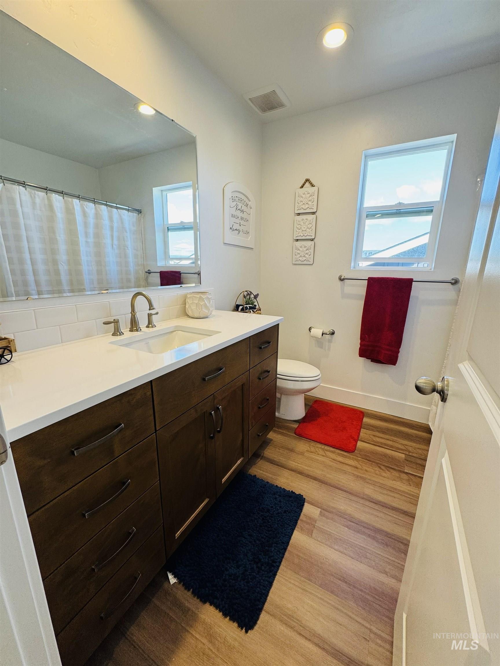 Full bathroom featuring vanity, light wood-type flooring, a shower with curtain, and recessed lighting
