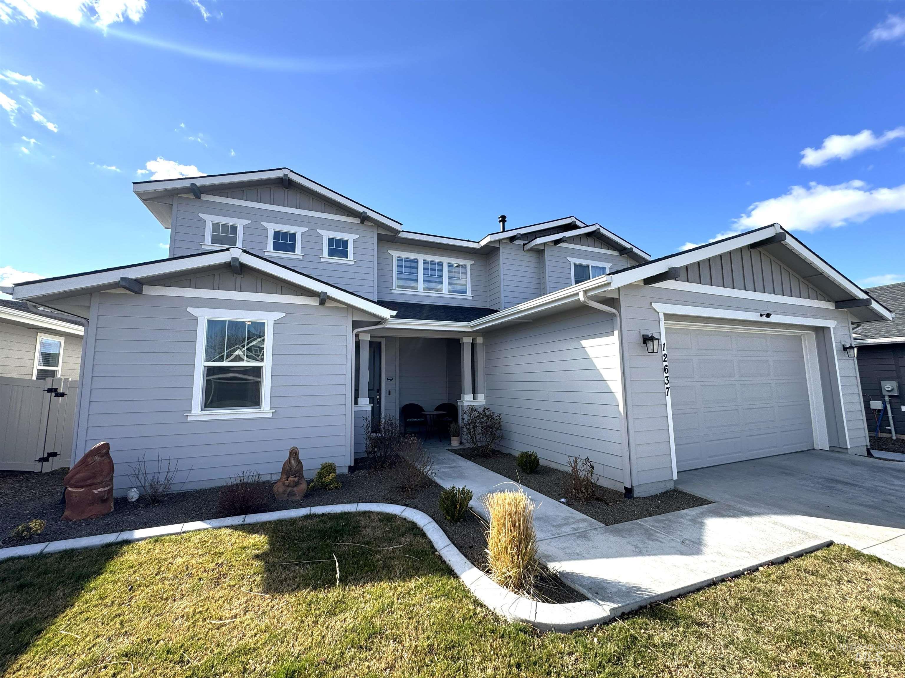 View of front facade with board and batten siding, a garage, a front lawn, driveway, and a porch