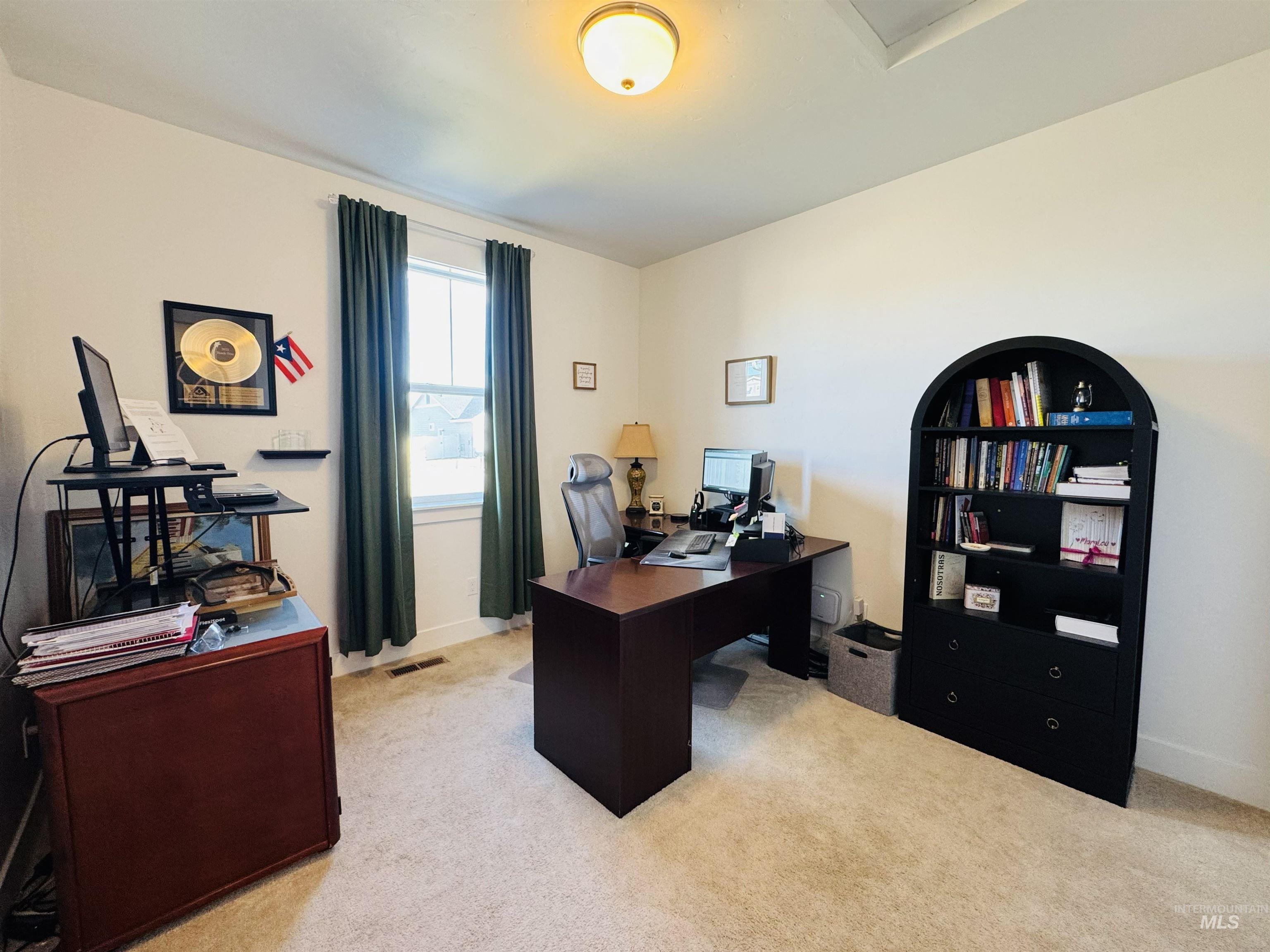 Carpeted home office featuring baseboards