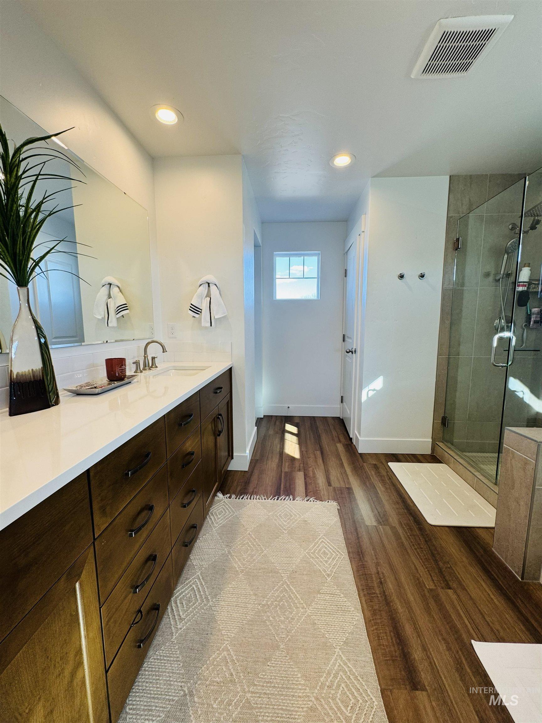 Bathroom featuring vanity, dark wood-style flooring, a shower stall, and recessed lighting