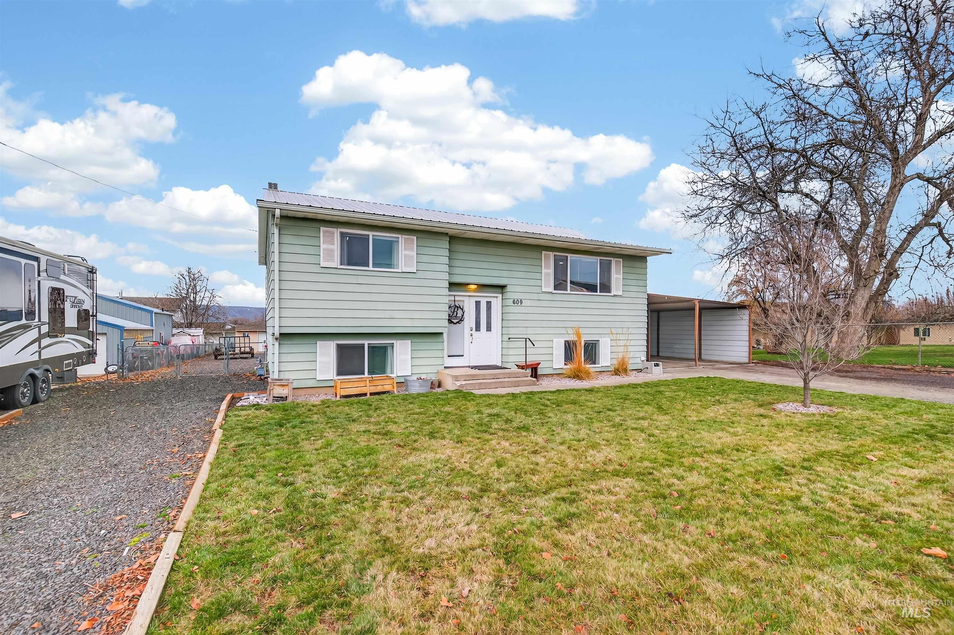 Raised ranch featuring driveway, an attached carport, and a metal roof