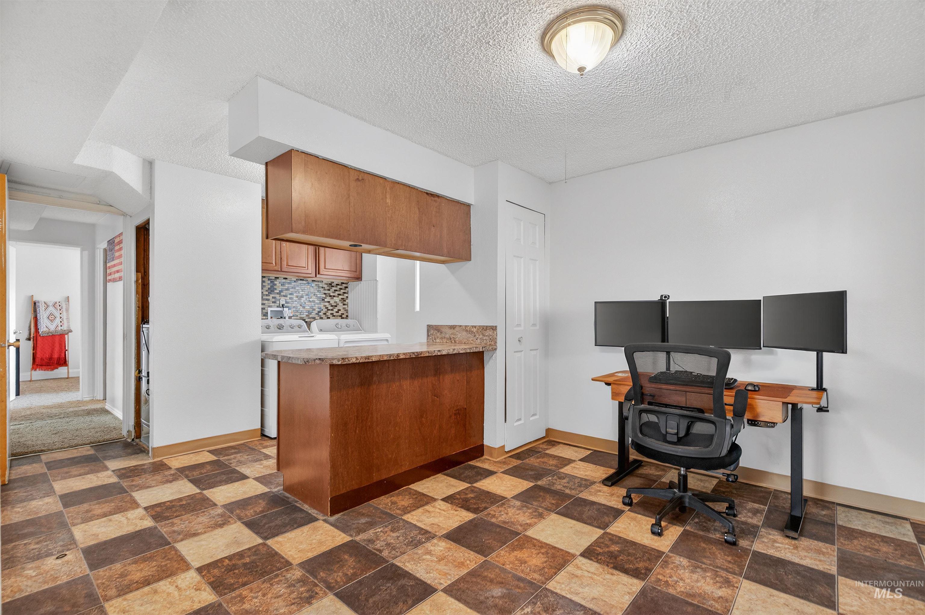Office area featuring a textured ceiling and washing machine and clothes dryer