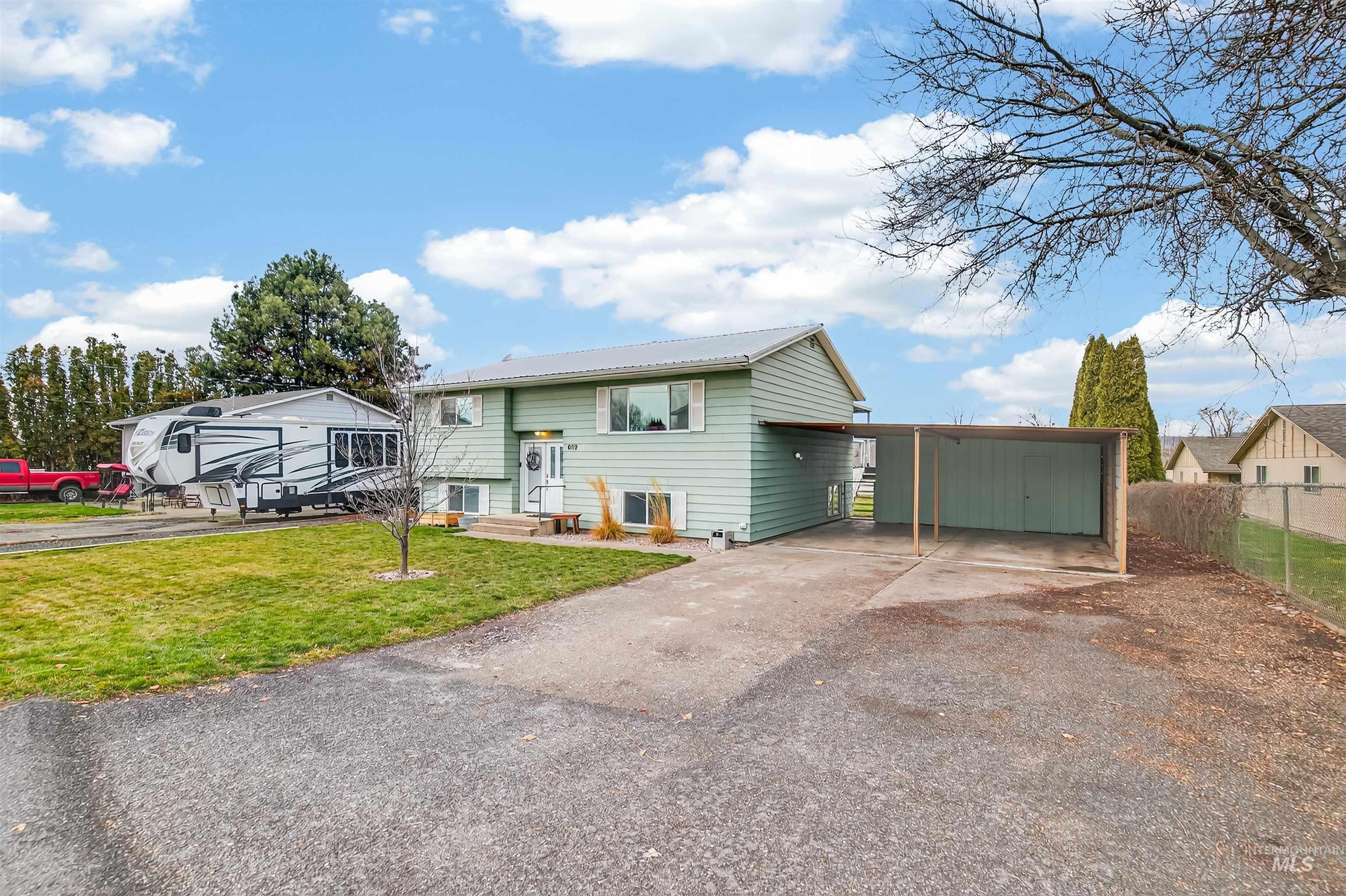 Raised ranch with asphalt driveway, an attached carport, and a metal roof