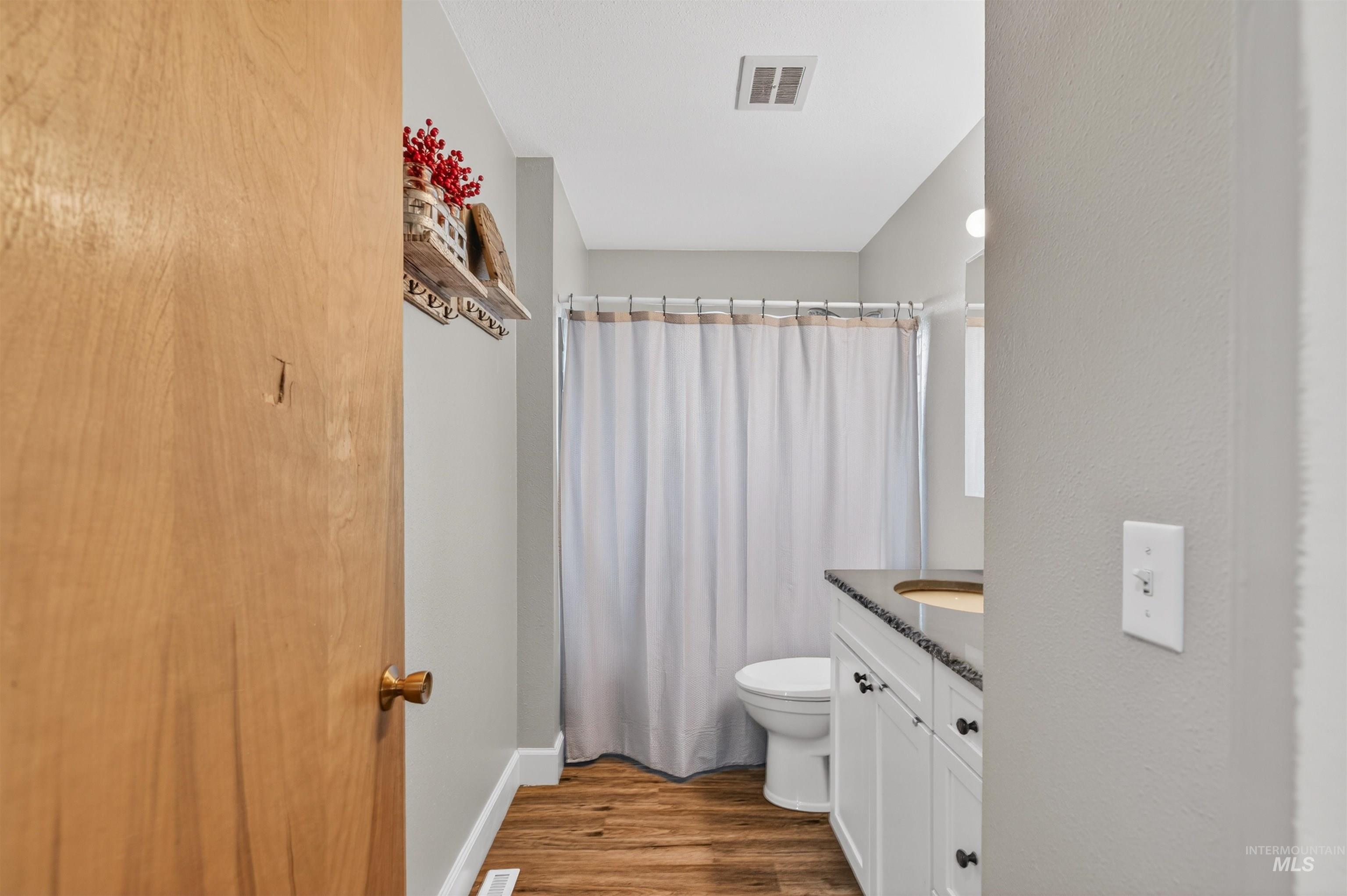 Bathroom with vanity, a shower with shower curtain, and dark wood finished floors