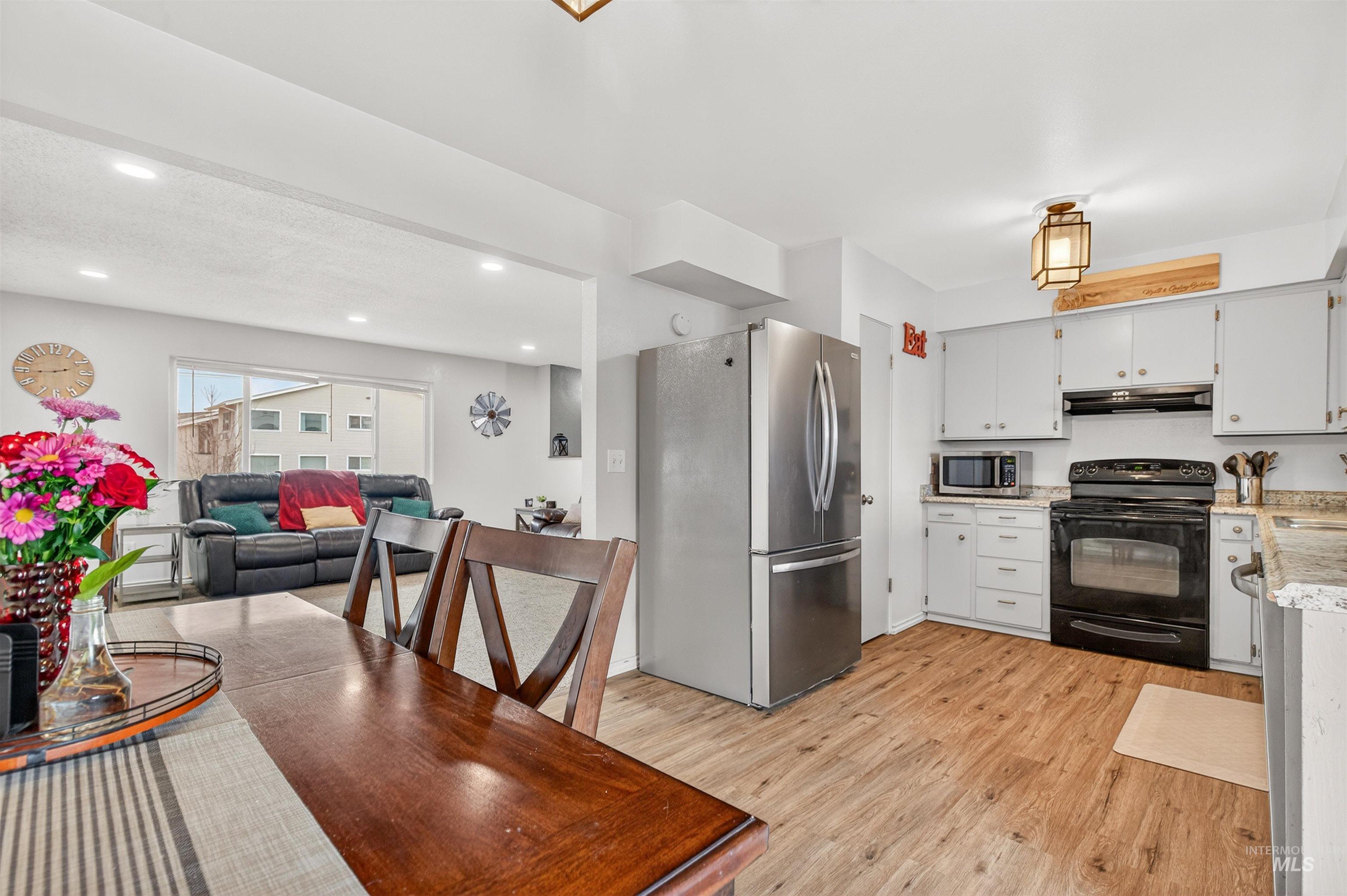 Kitchen with stainless steel appliances, light wood-style floors, open floor plan, recessed lighting, and white cabinets