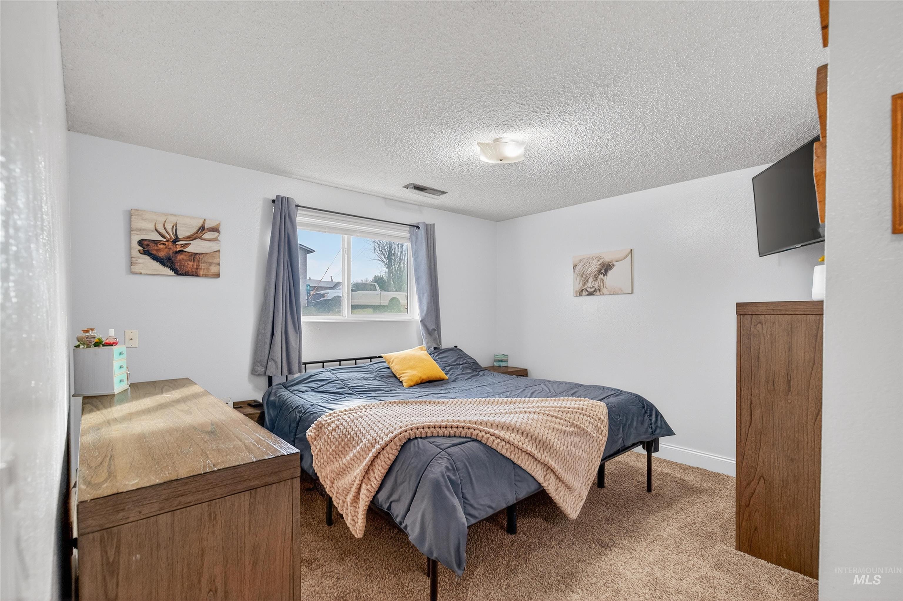 Carpeted bedroom with a textured ceiling and baseboards