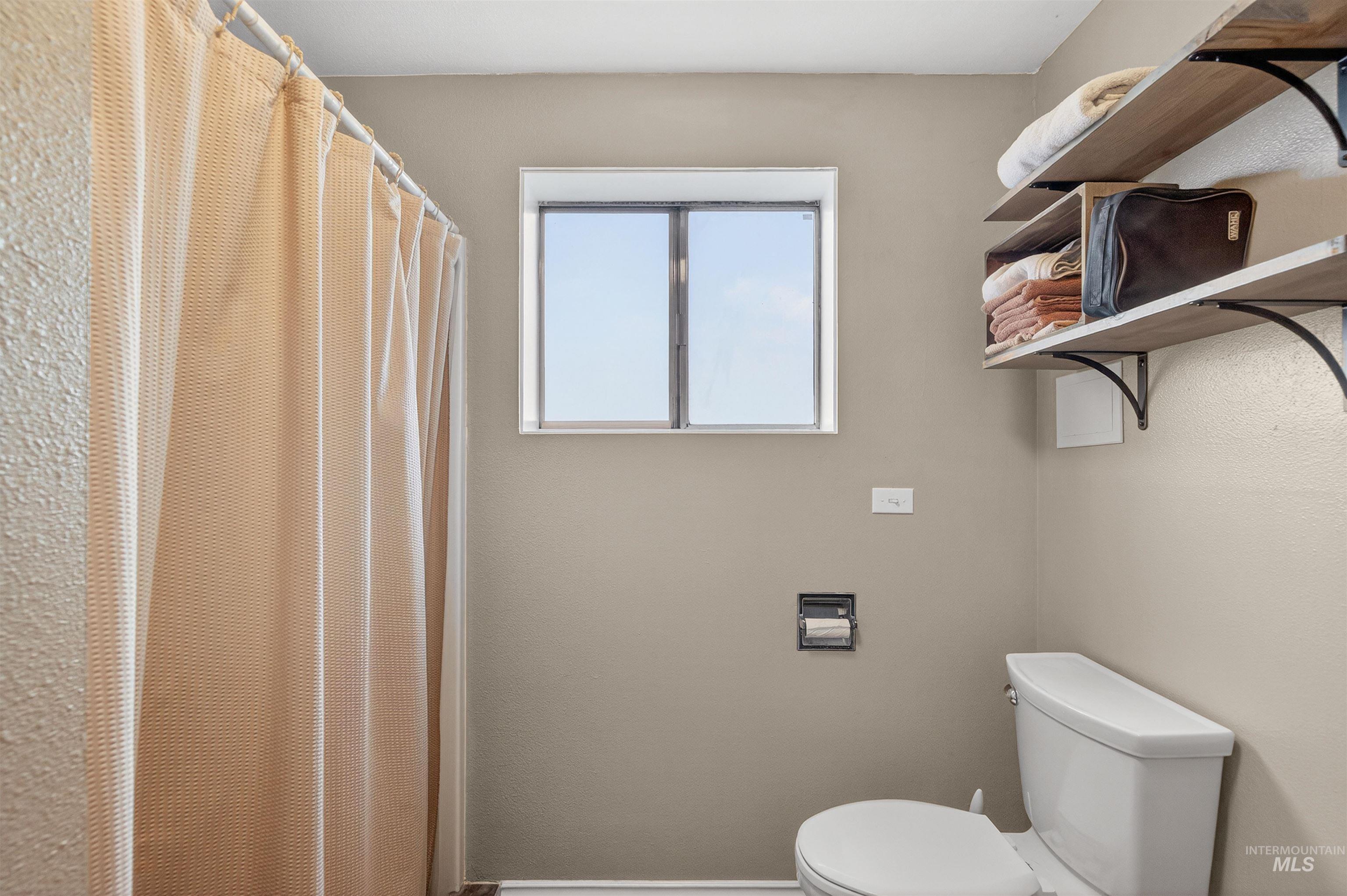 Bathroom featuring a shower with curtain and toilet