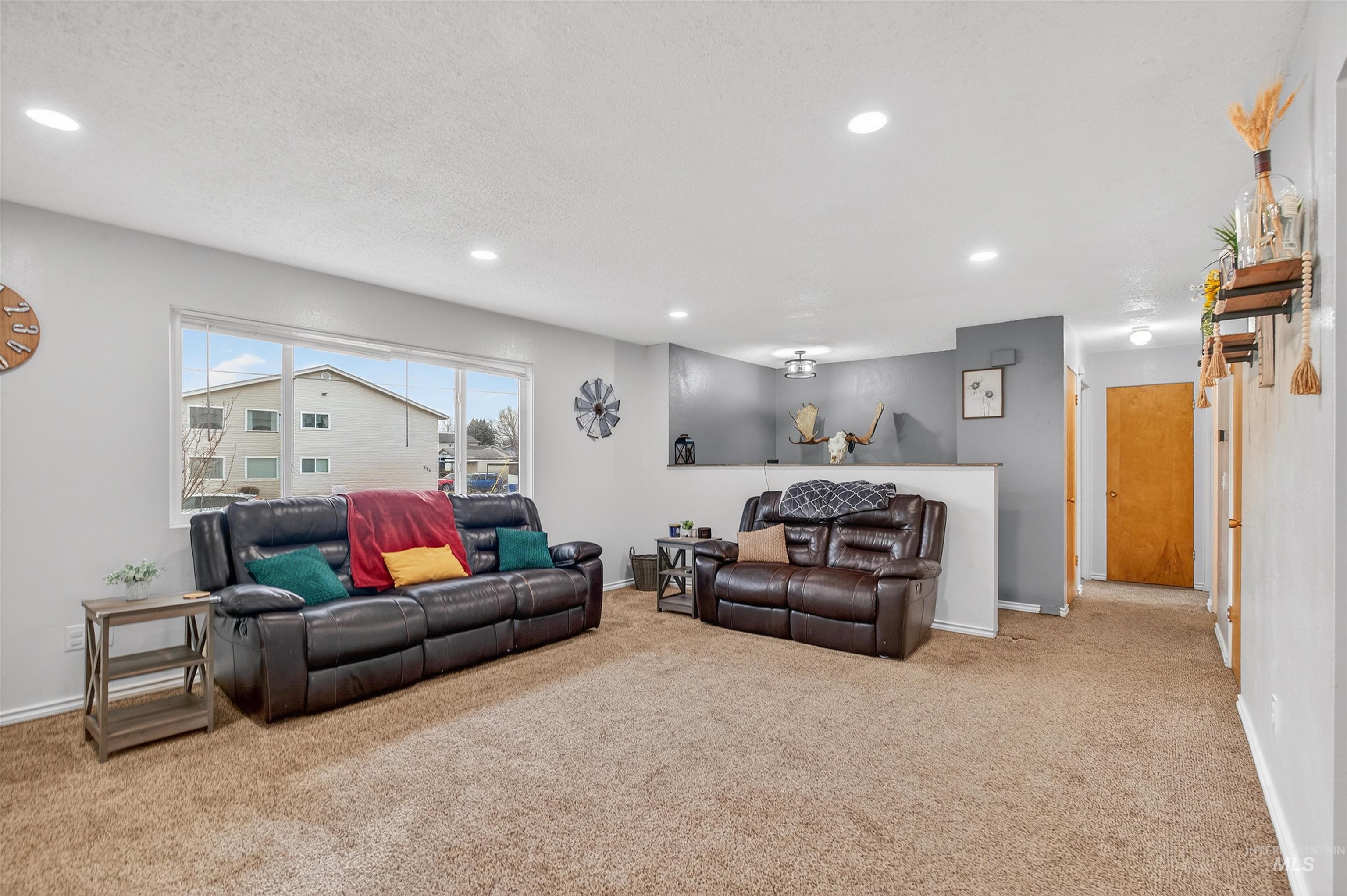 Living area featuring carpet flooring, recessed lighting, and a textured ceiling