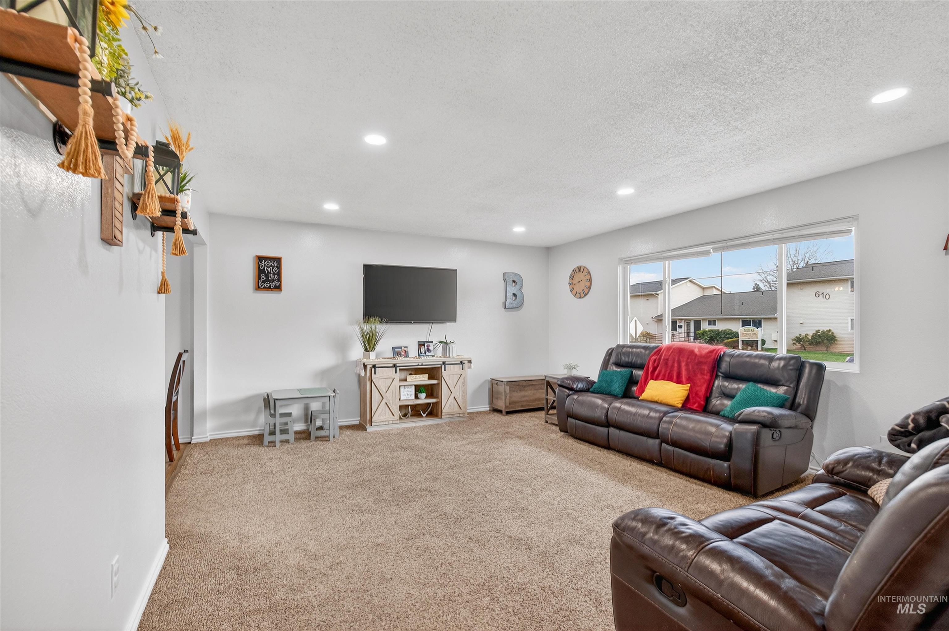 Carpeted living area featuring recessed lighting and a textured ceiling